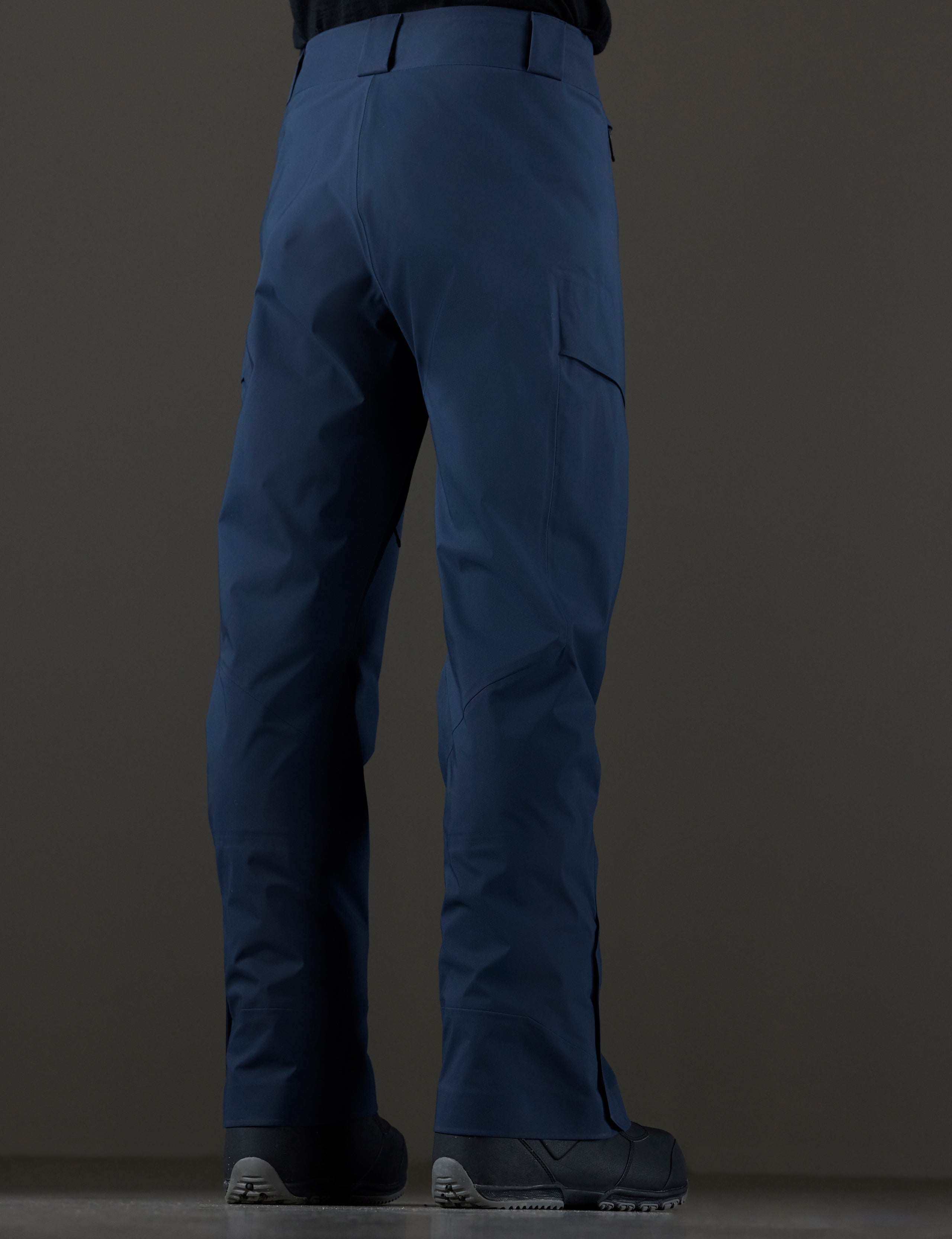 Rear 3/4 lower body view of man wearing Maverick Snow-Shell Pant in Total Eclipse dark blue from AETHER Apparel.