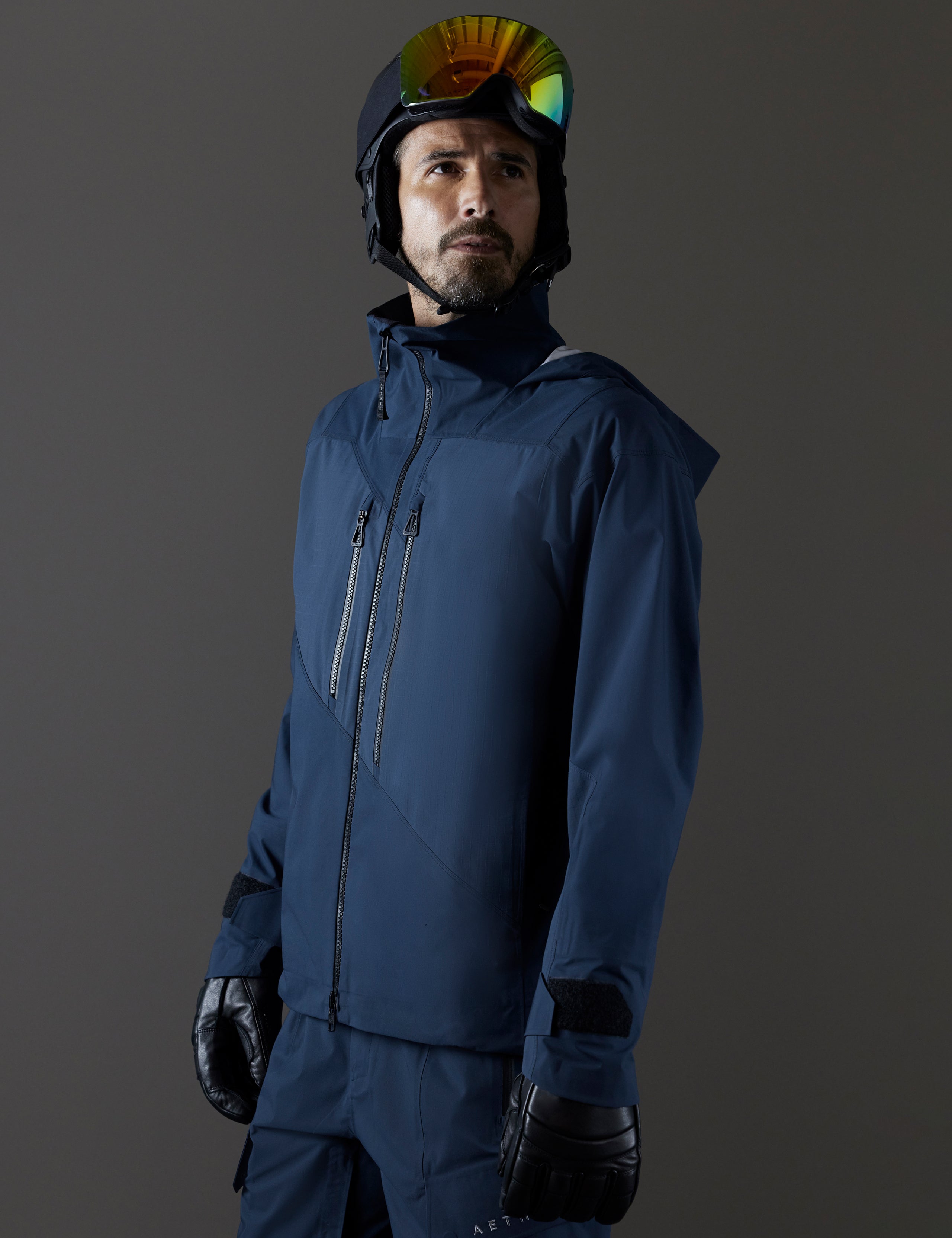 Front 3/4 body view of man wearing Maverick Snow-Shell Jacket in Total Eclipse dark blue from AETHER Apparel.
