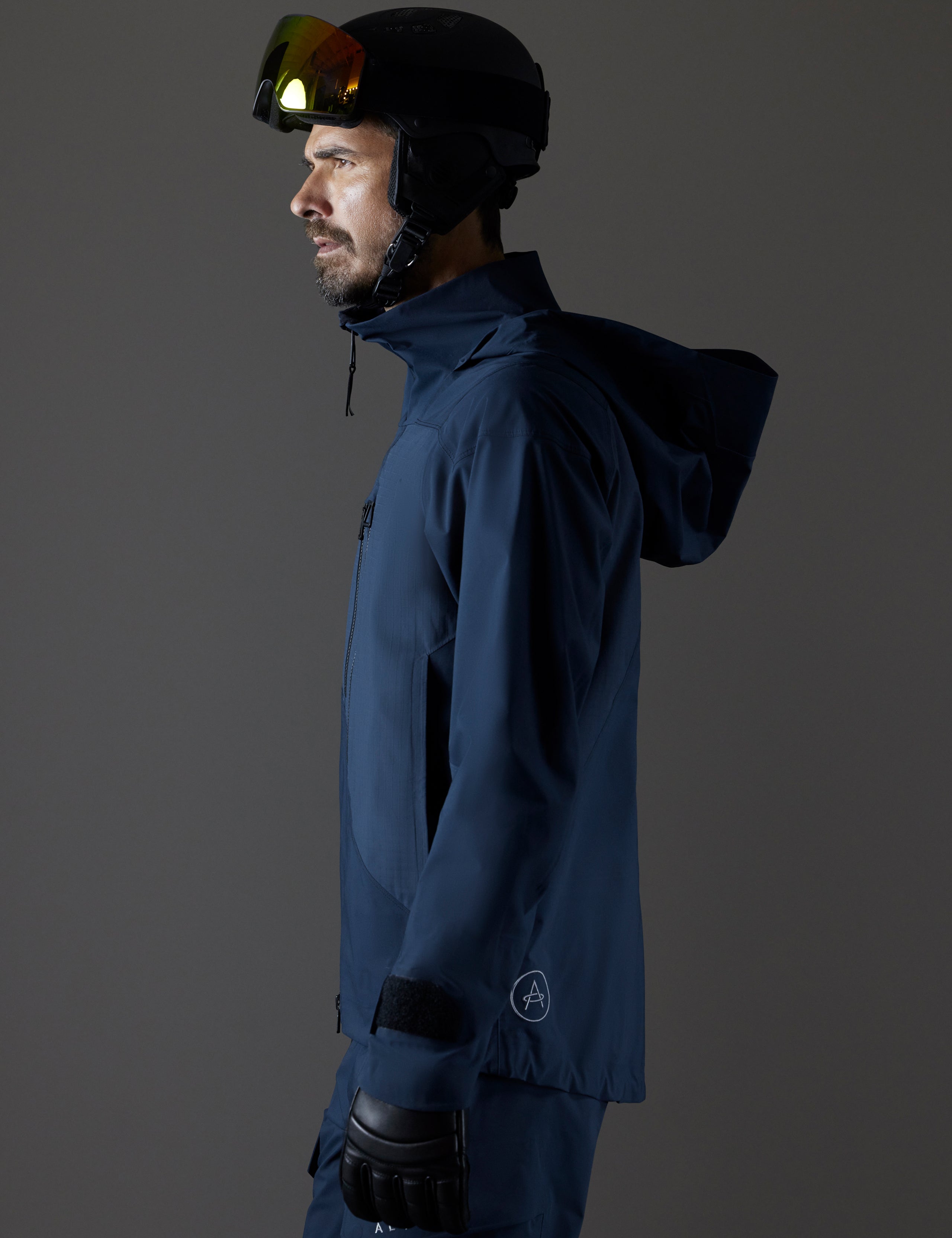 Side profile body view of man wearing Maverick Snow-Shell Jacket in Total Eclipse dark blue from AETHER Apparel.