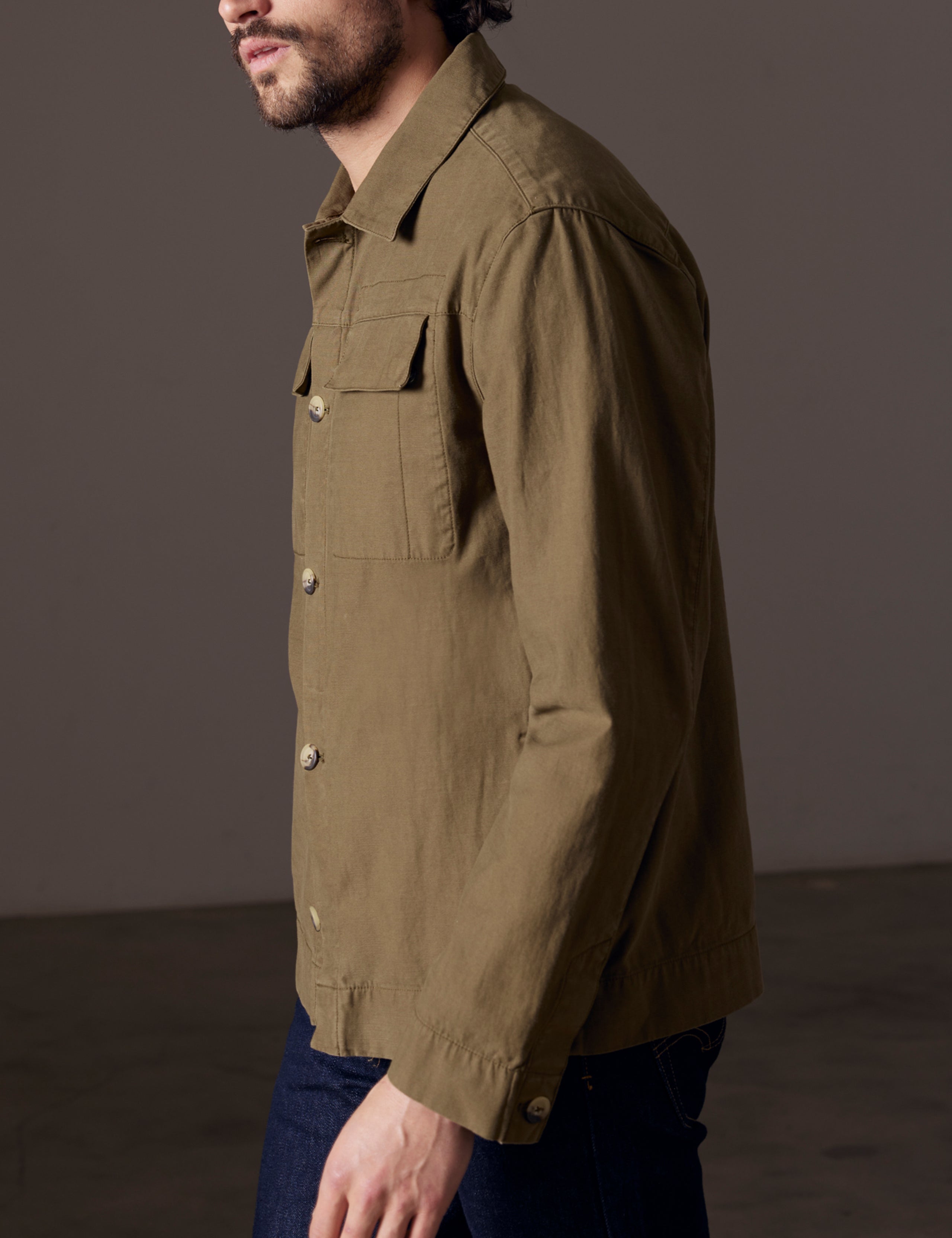 Side profile body view of man wearing Mesa Jacket in Command Green from AETHER Apparel.