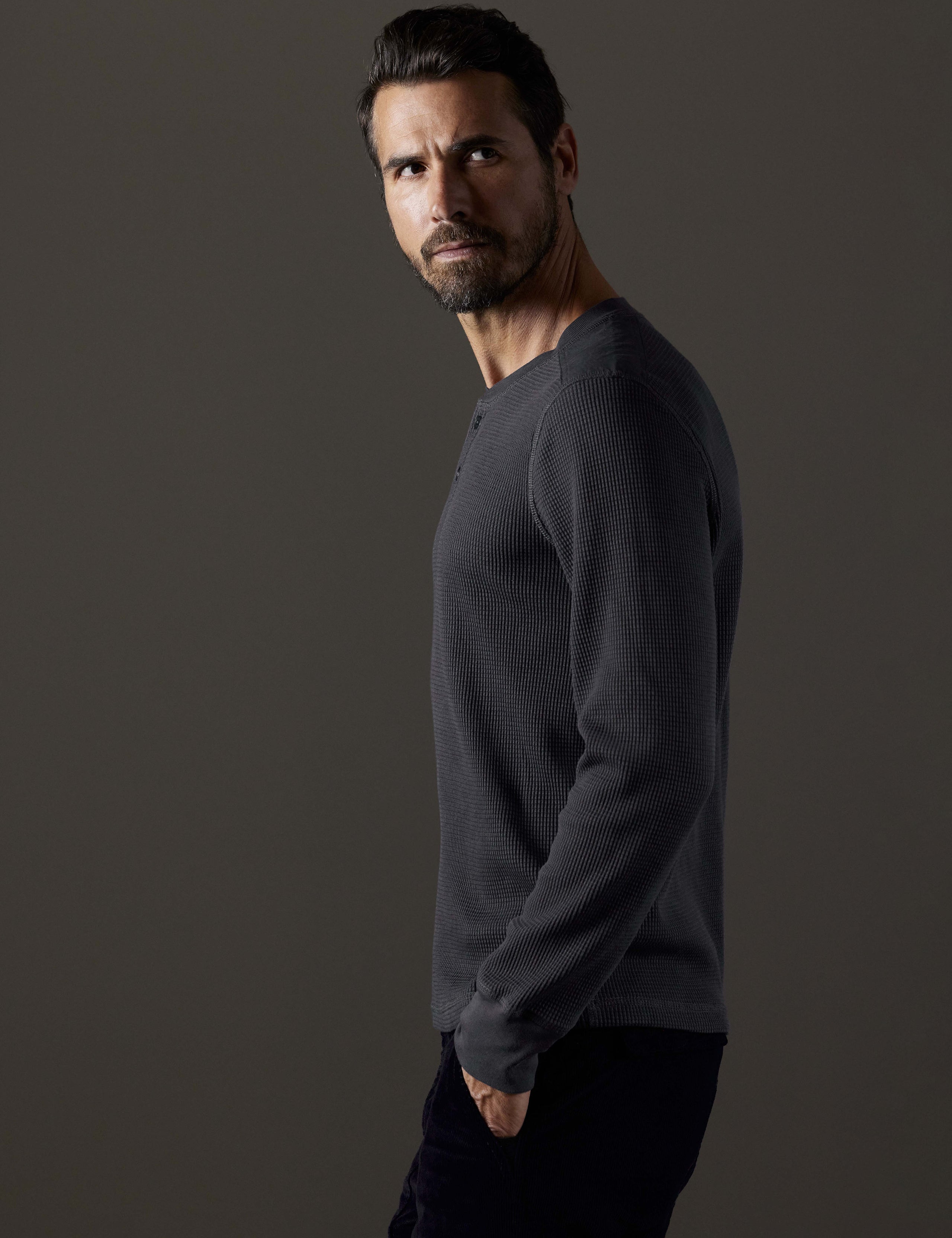 Side profile body view of man wearing Milford Waffle Henley in Graphite from AETHER Apparel.