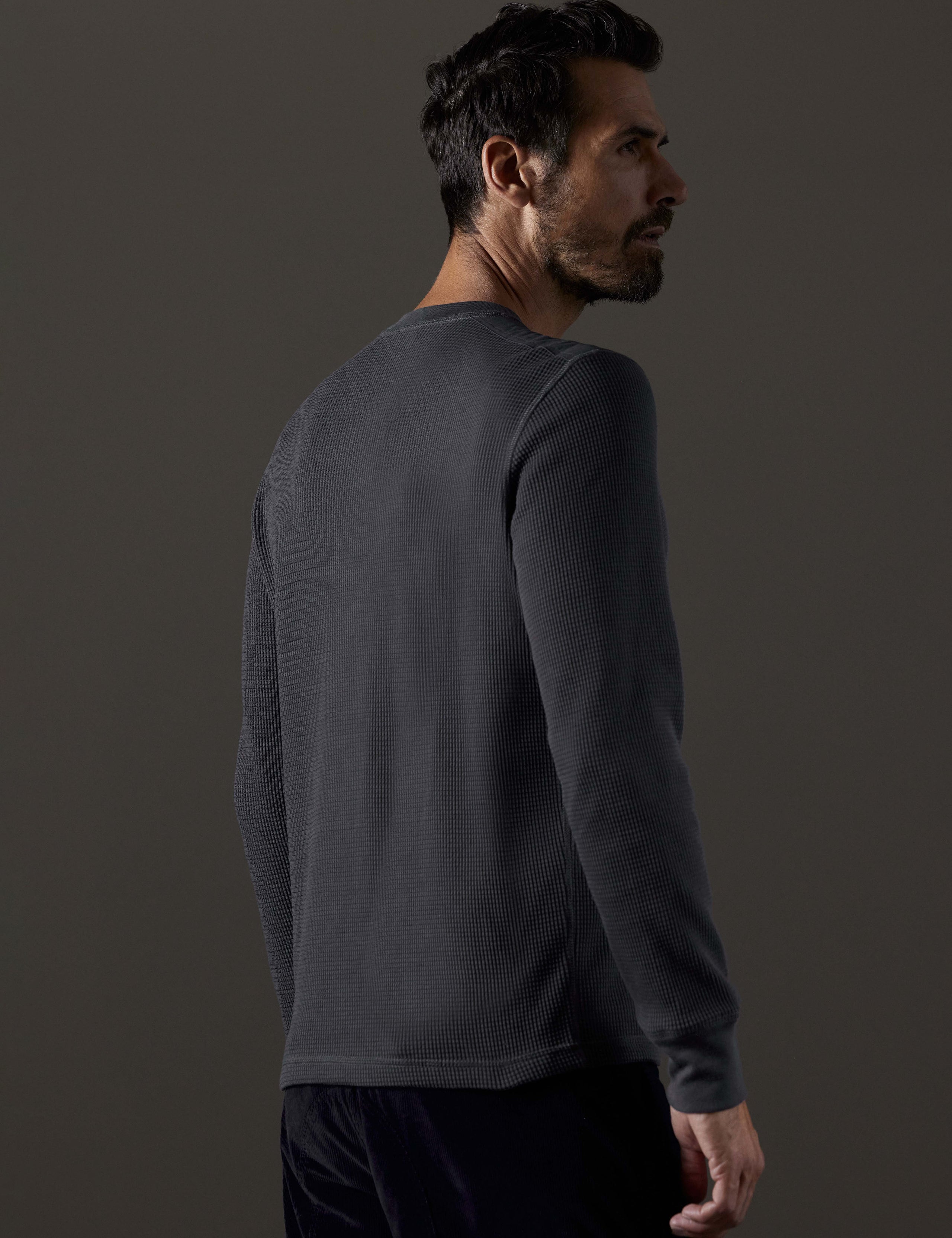 Rear 3/4 body view of man wearing Milford Waffle Henley in Graphite from AETHER Apparel.