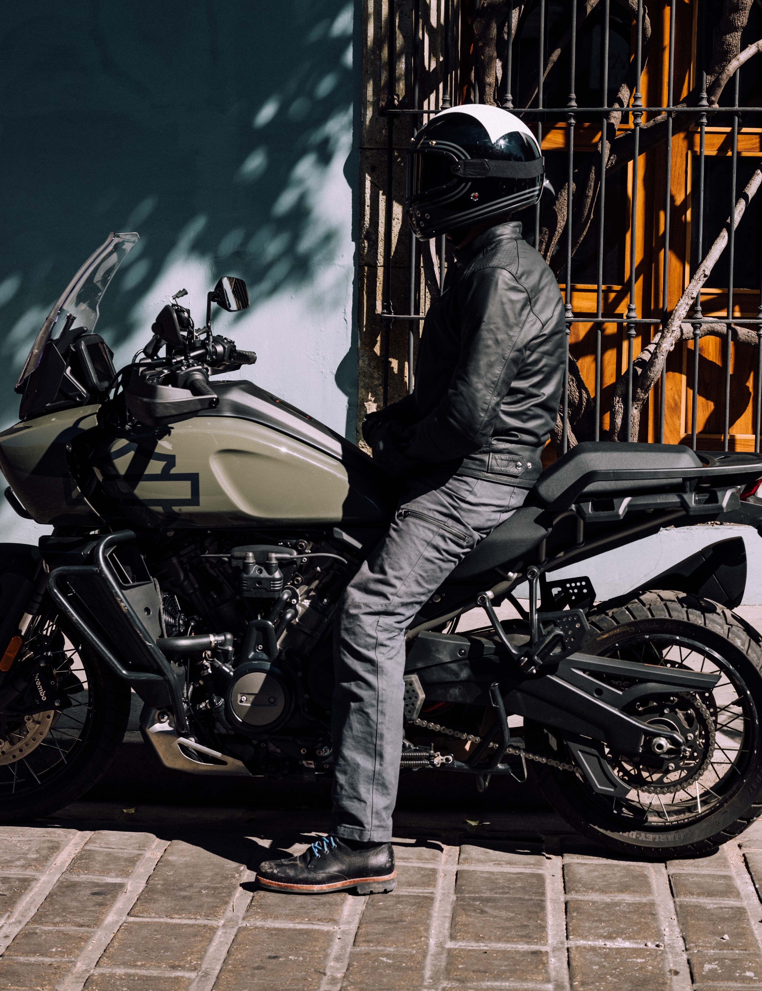 Outdoor lifestyle image of man sitting on Harley-Davidson adventure motorcycle wearing AETHER Moto Boot in Jet Black from AETHER Apparel.