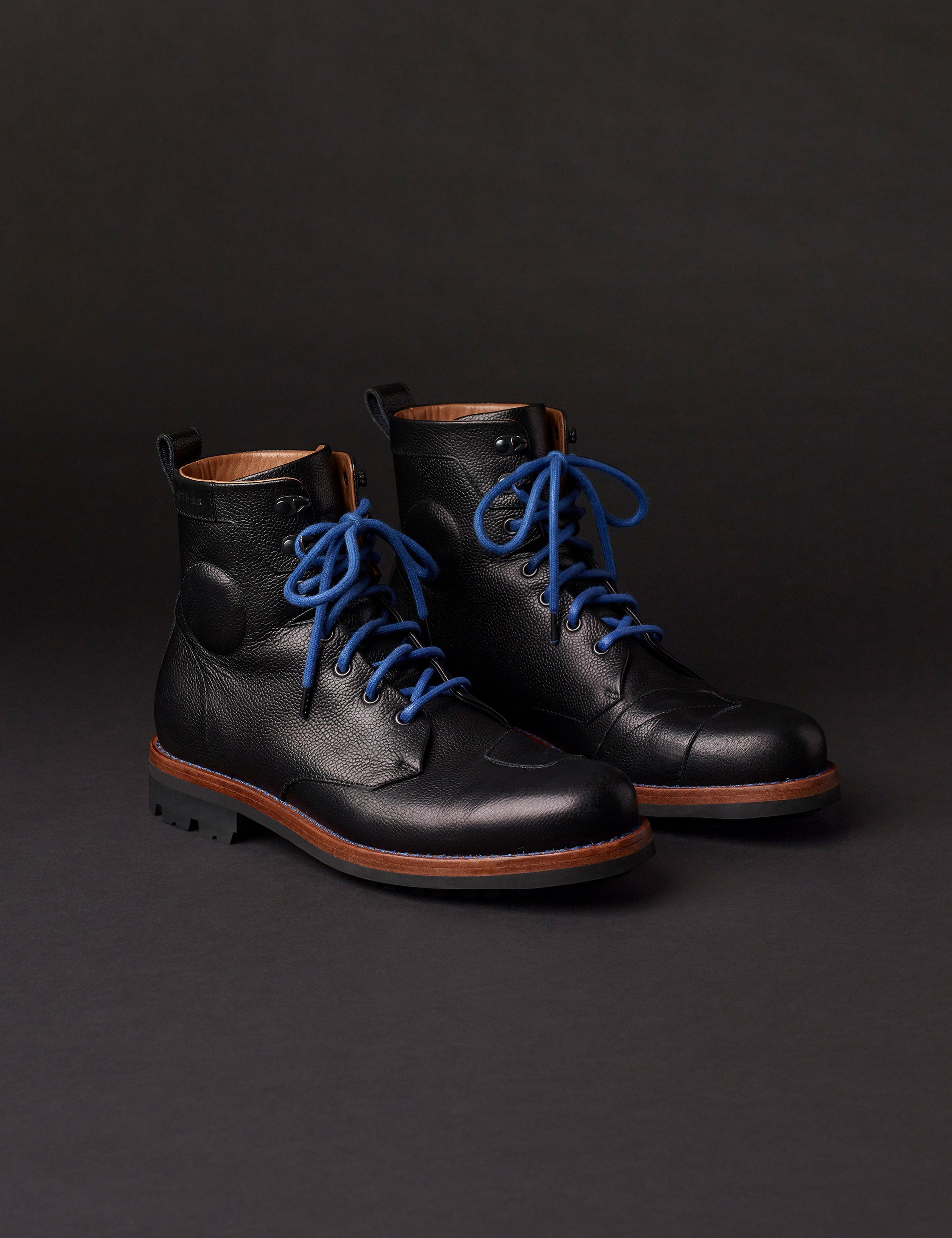 Front angled view of AETHER Moto Boot in Jet Black with blue laces from AETHER Apparel.