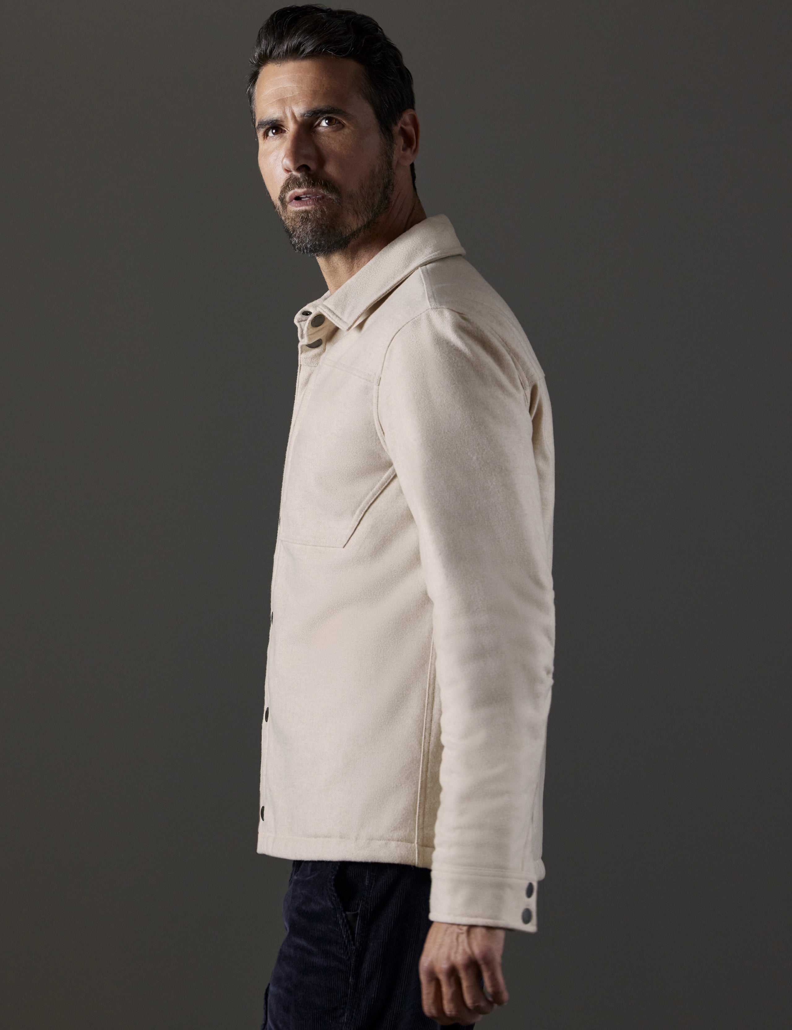 Side profile body view of man wearing Nova Insulated Button-Down in Bone Heather white from AETHER Apparel.