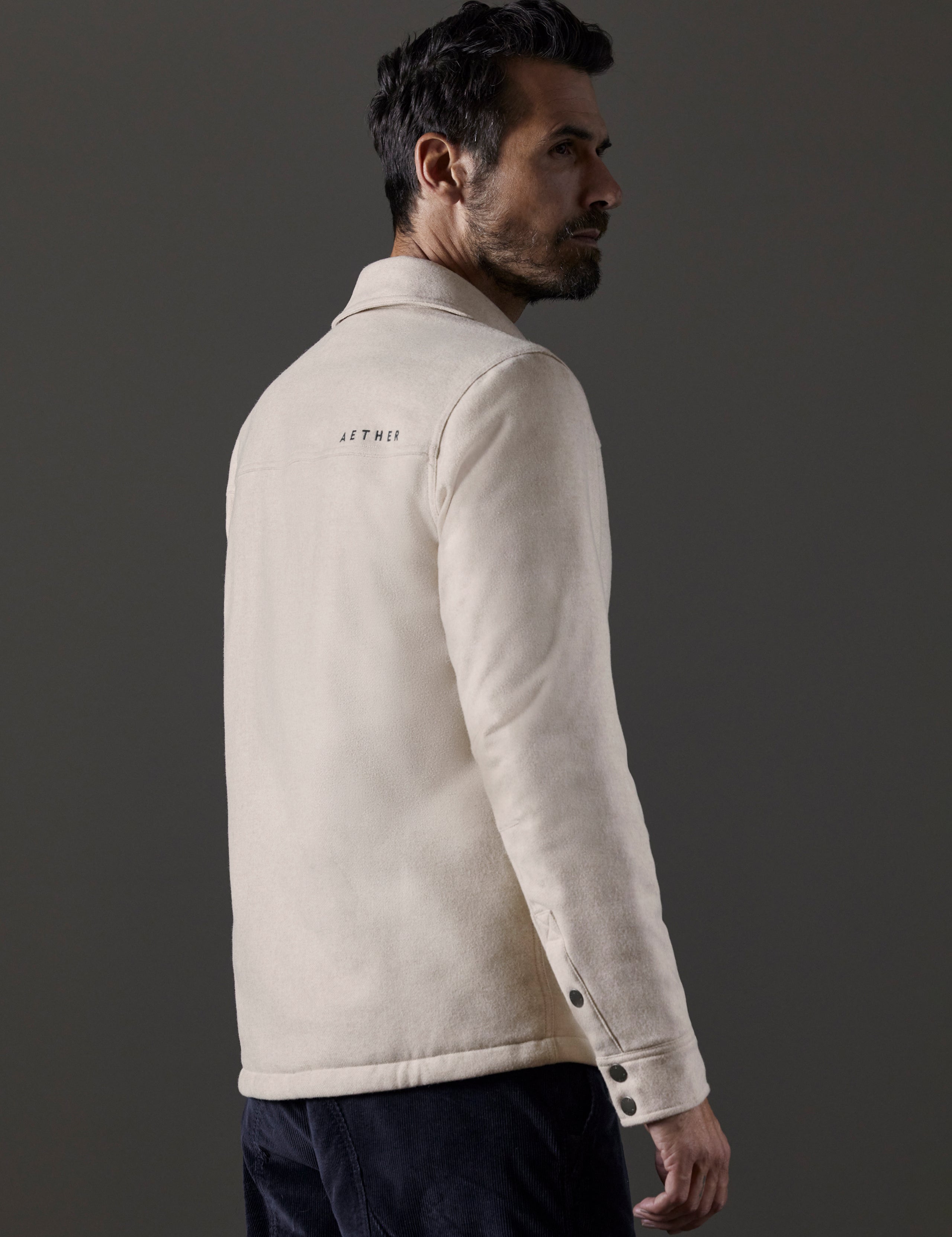 Rear 3/4 body view of man wearing Nova Insulated Button-Down in Bone Heather white from AETHER Apparel.