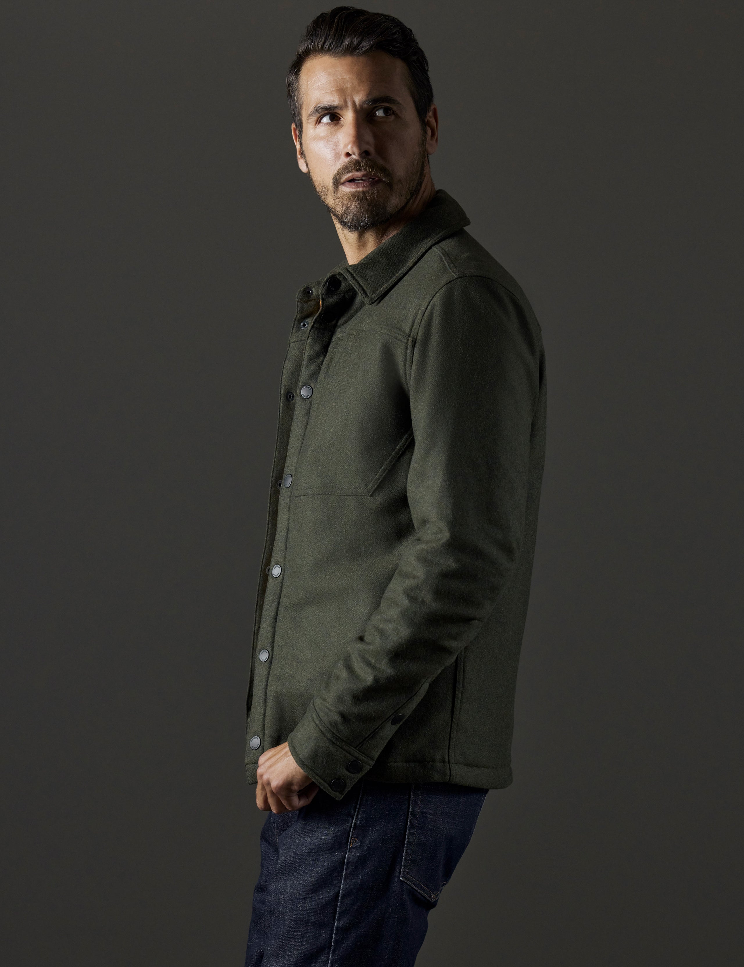 Side profile body view of man wearing Nova Insulated Button-Down in Command Green from AETHER Apparel.
