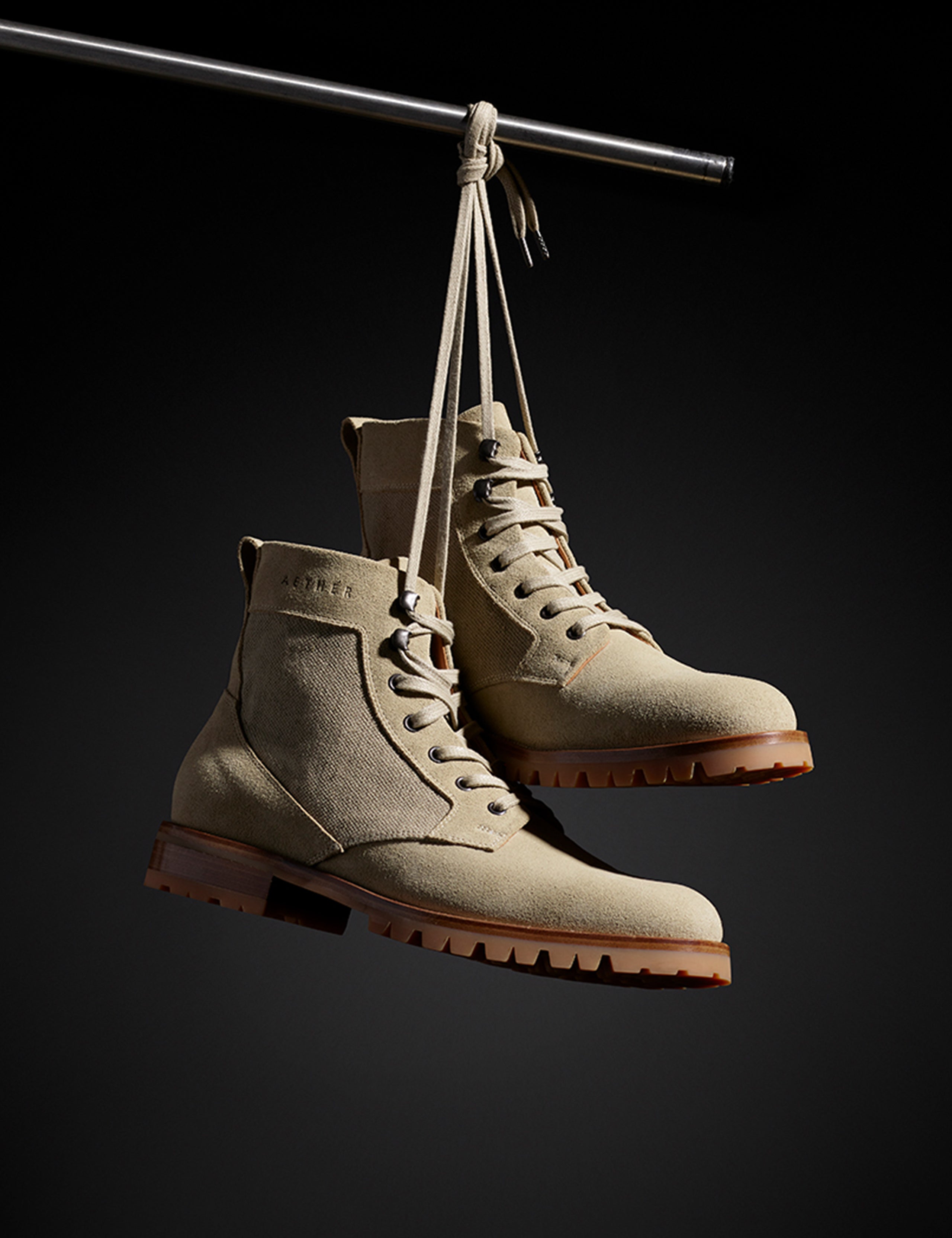 Front angled view of Ojai City Boot in Natural suede and canvas from AETHER Apparel hanging from shoelaces on wire. 