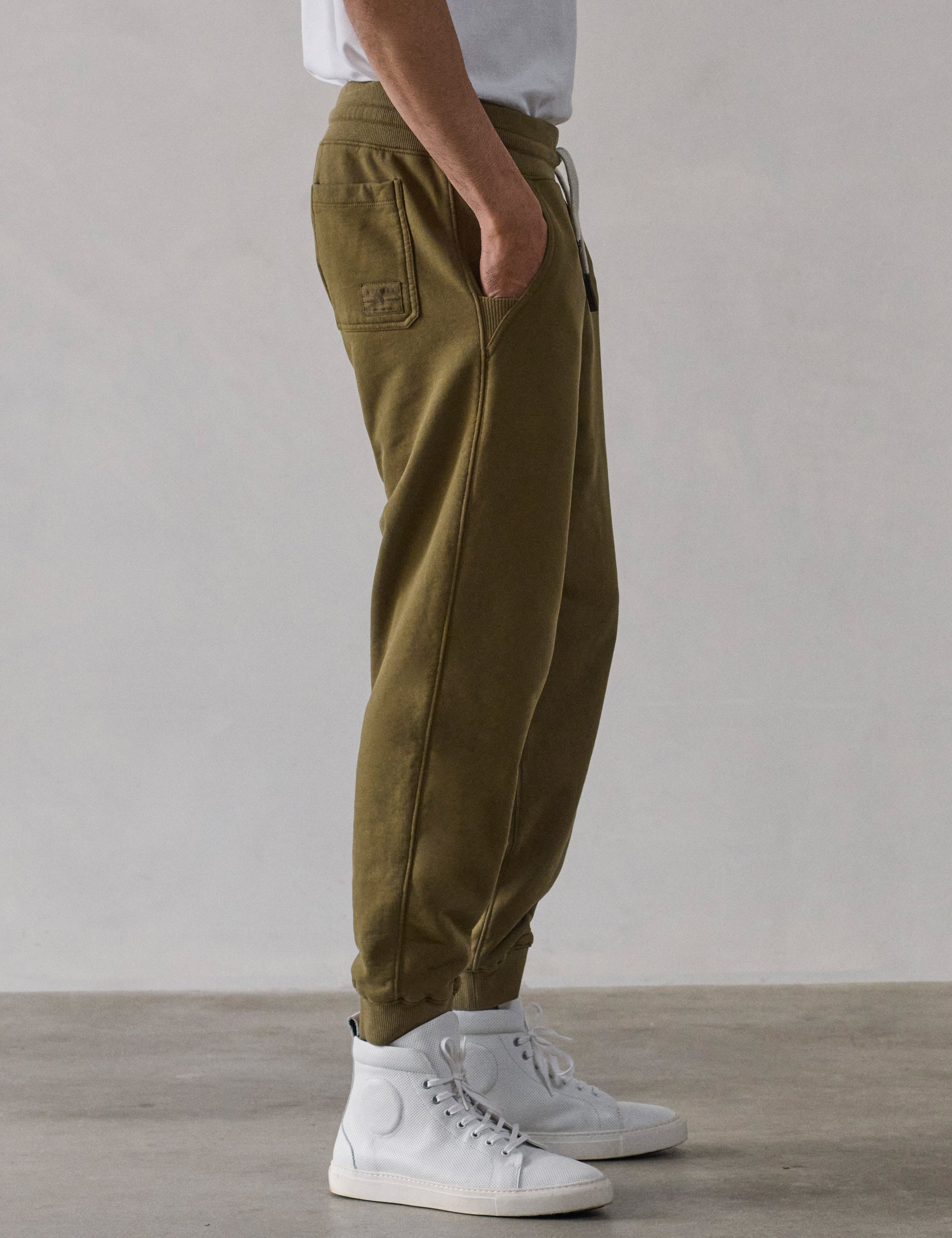 Right side profile lower-body view of man wearing Osa Cuffed Sweatpant in Command Green from AETHER Apparel.