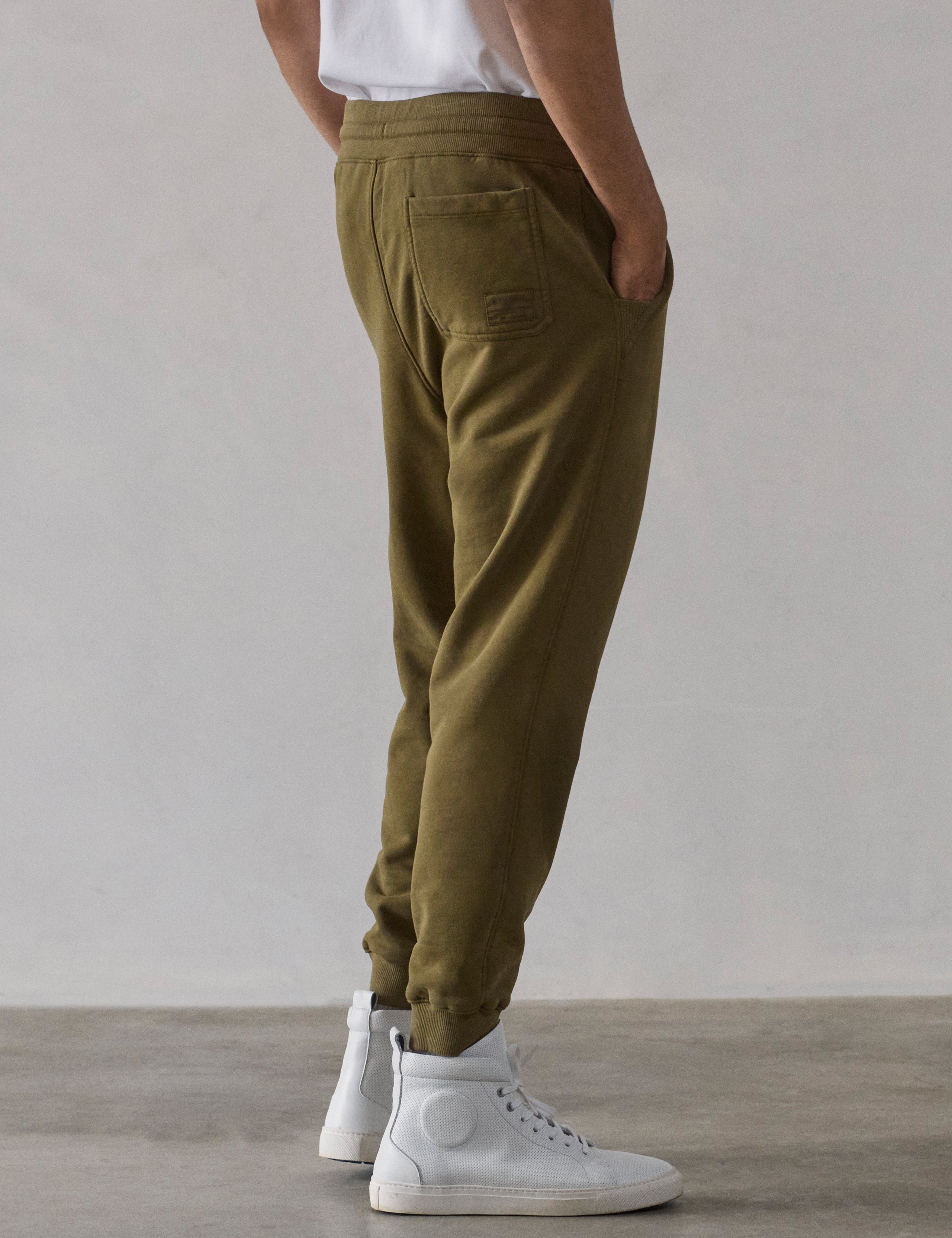 Rear 3/4 lower-body view of man wearing Osa Cuffed Sweatpant in Command Green from AETHER Apparel.