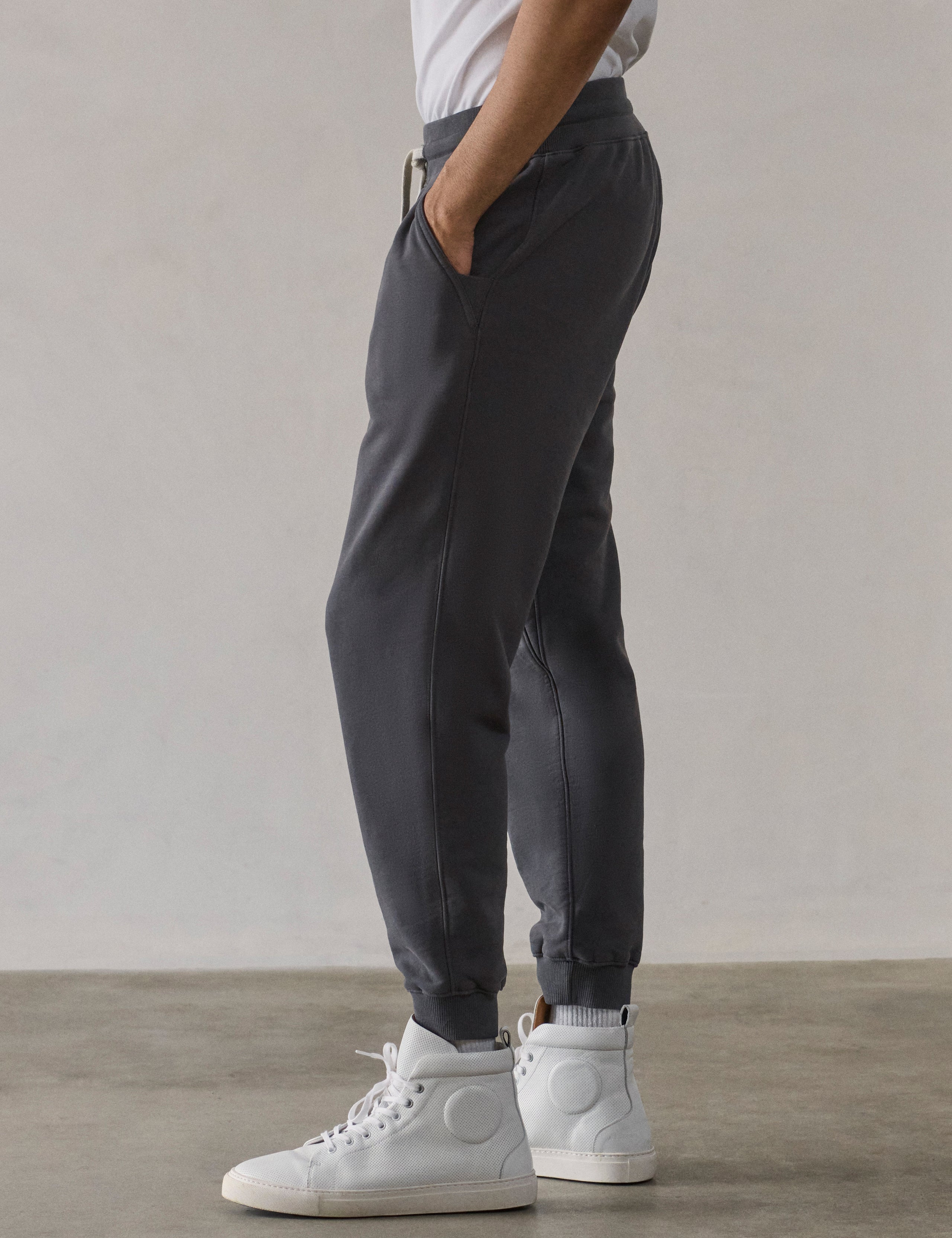 Left side profile lower-body view of man wearing Osa Cuffed Sweatpant in Graphite grey from AETHER Apparel.