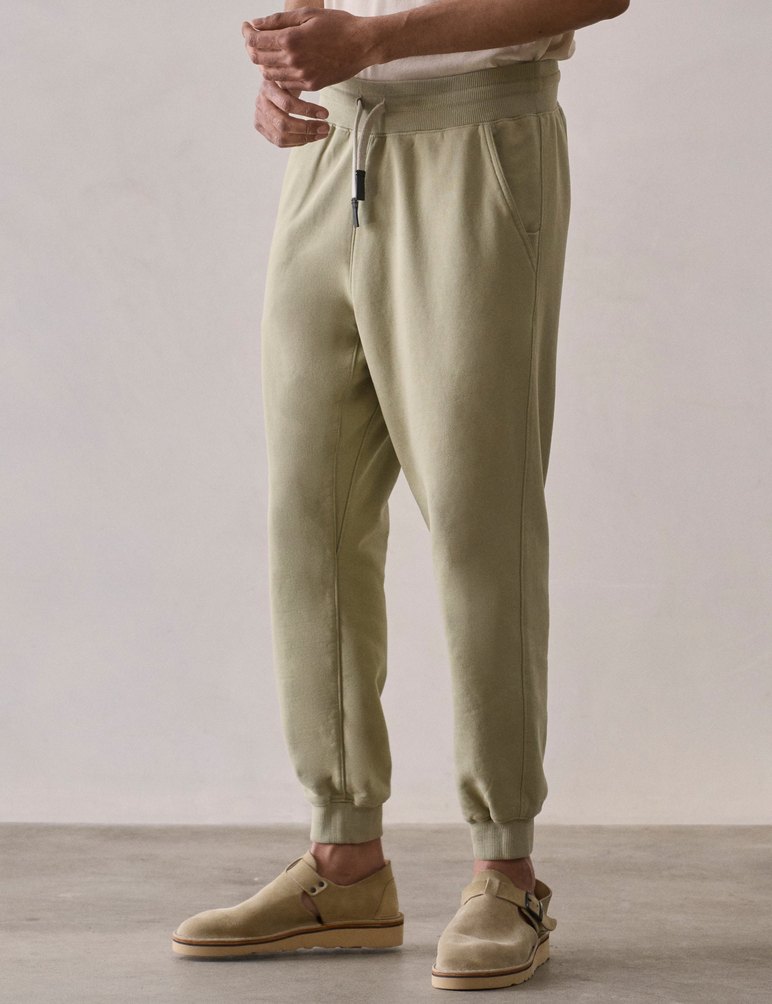 Front 3/4 lower body view of man wearing Osa Cuffed Sweatpant in Sage Green from AETHER Apparel.