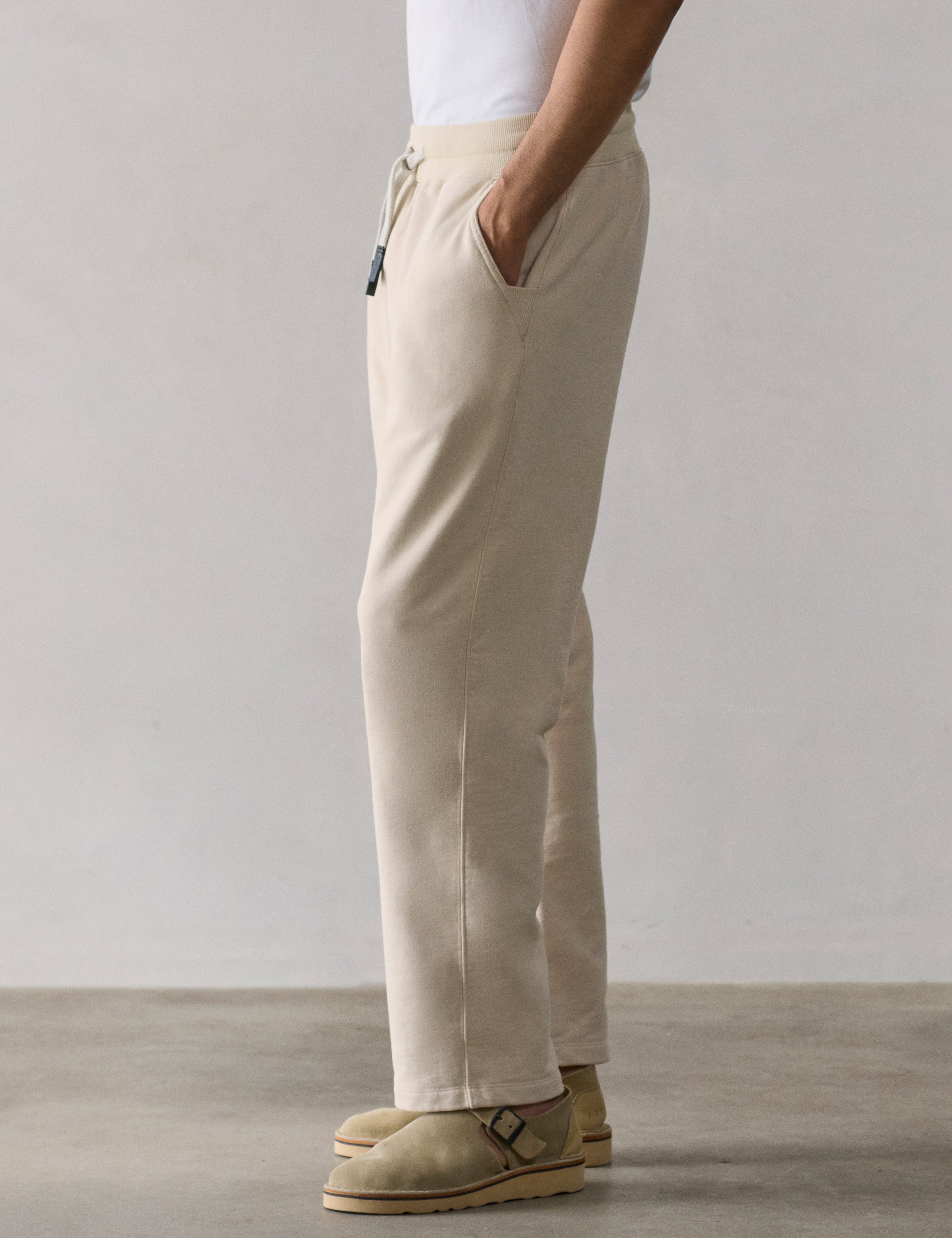 Left side lower body profile view of man wearing Osa Easy-Fit Sweatpant in Bone white from AETHER Apparel.