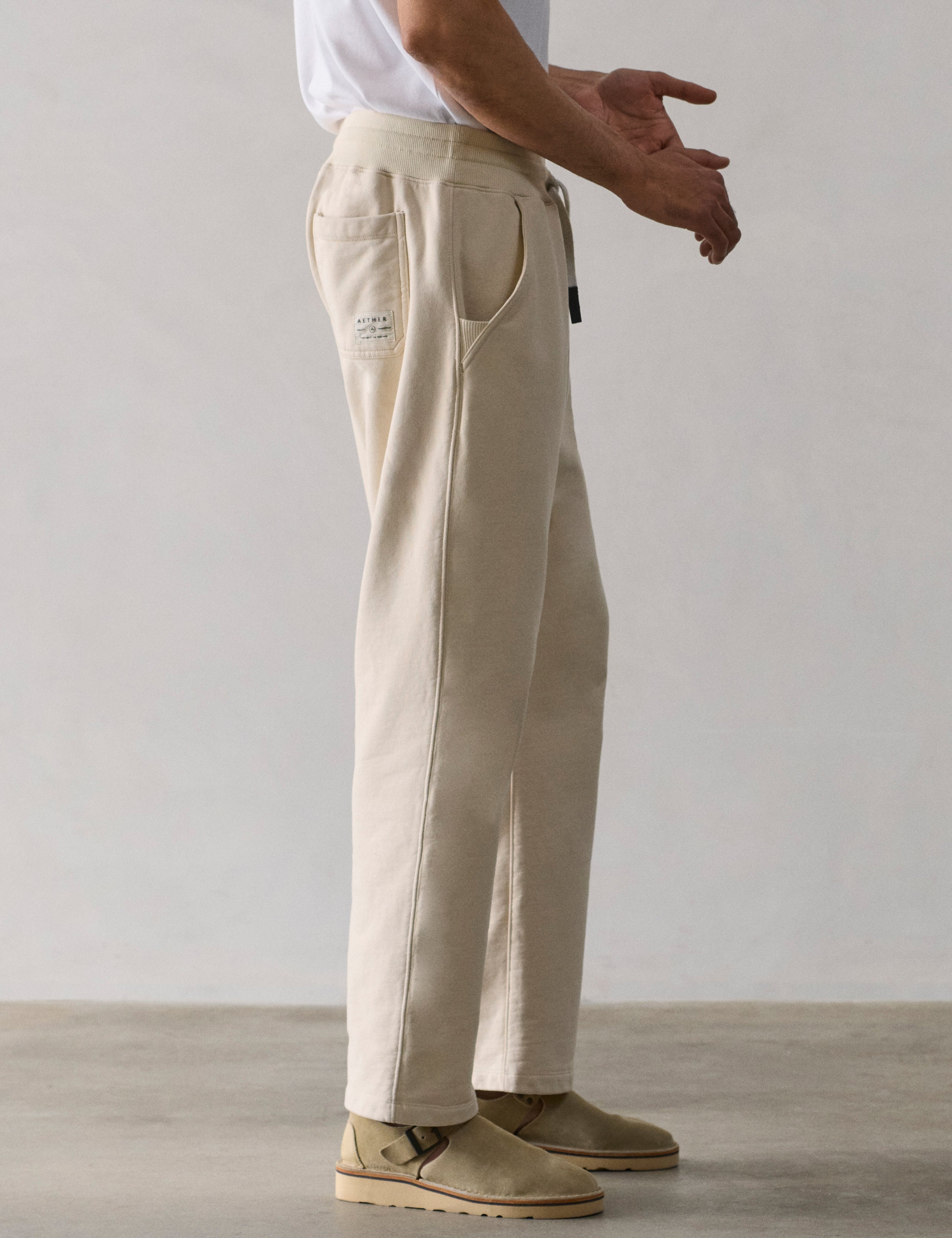 Right side lower body profile view of man wearing Osa Easy-Fit Sweatpant in Bone white from AETHER Apparel.