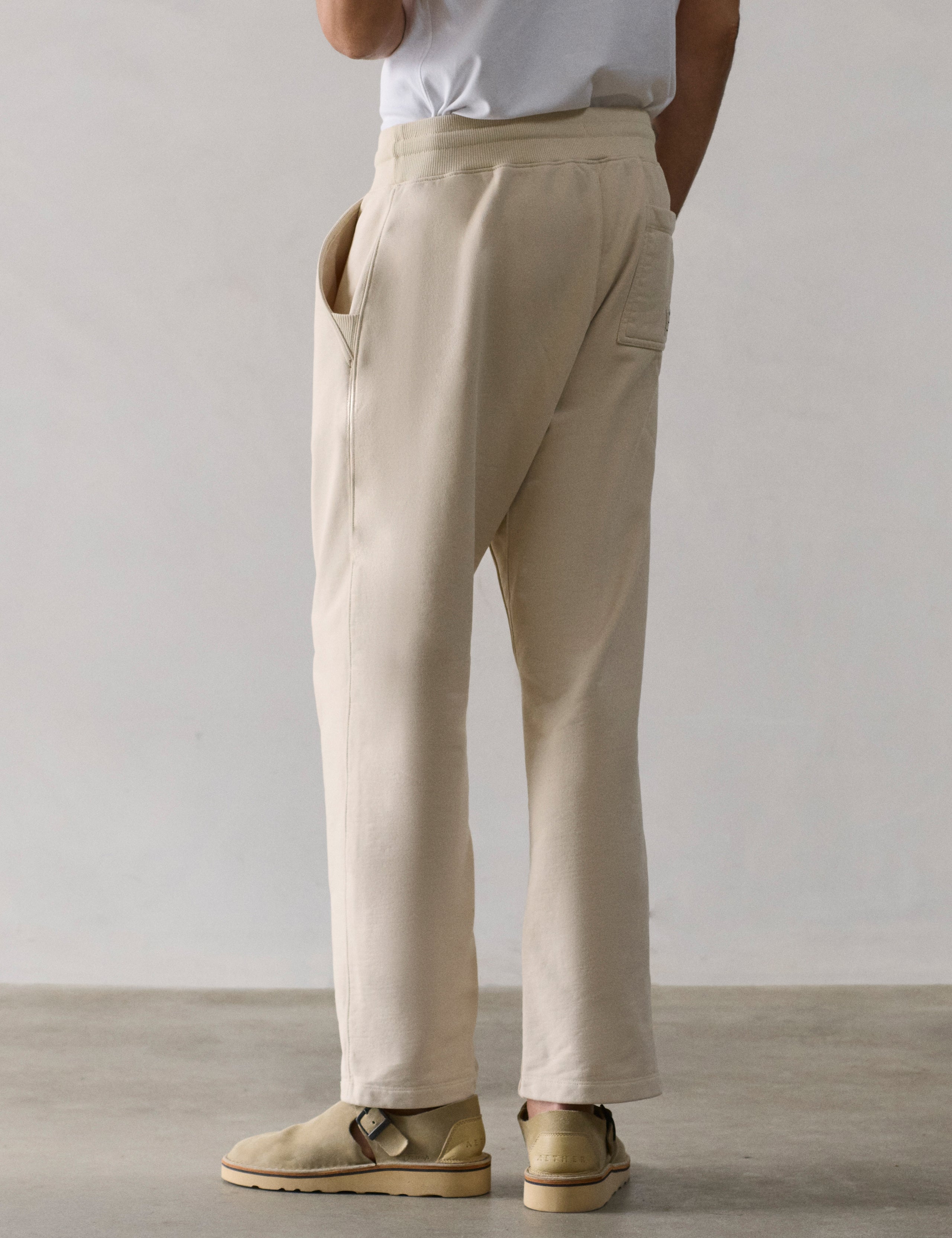 Rear 3/4 lower body view of man wearing Osa Easy-Fit Sweatpant in Bone white from AETHER Apparel.