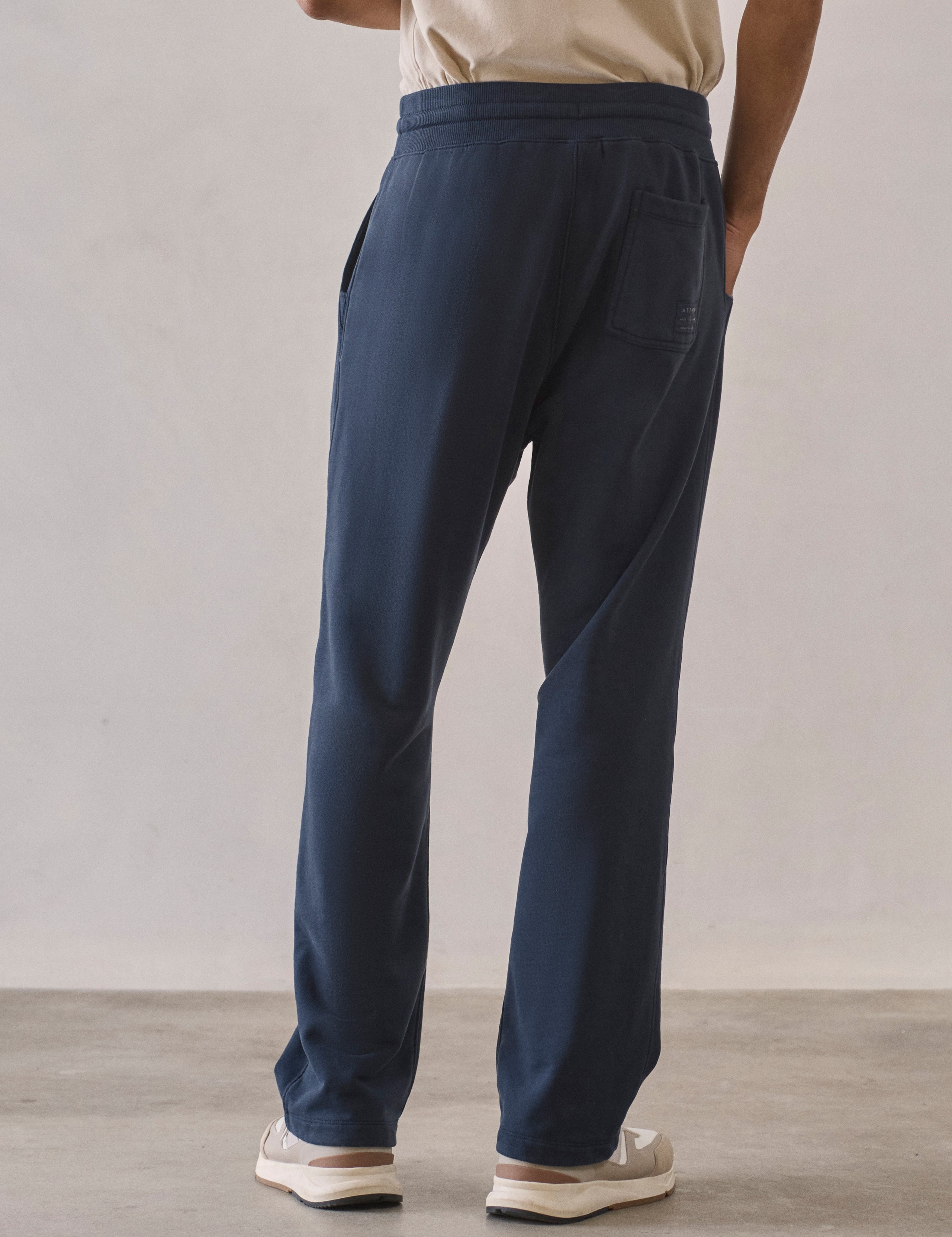 Rear lower body view of man wearing Osa Easy-Fit Sweatpant in Total Eclipse dark blue from AETHER Apparel.