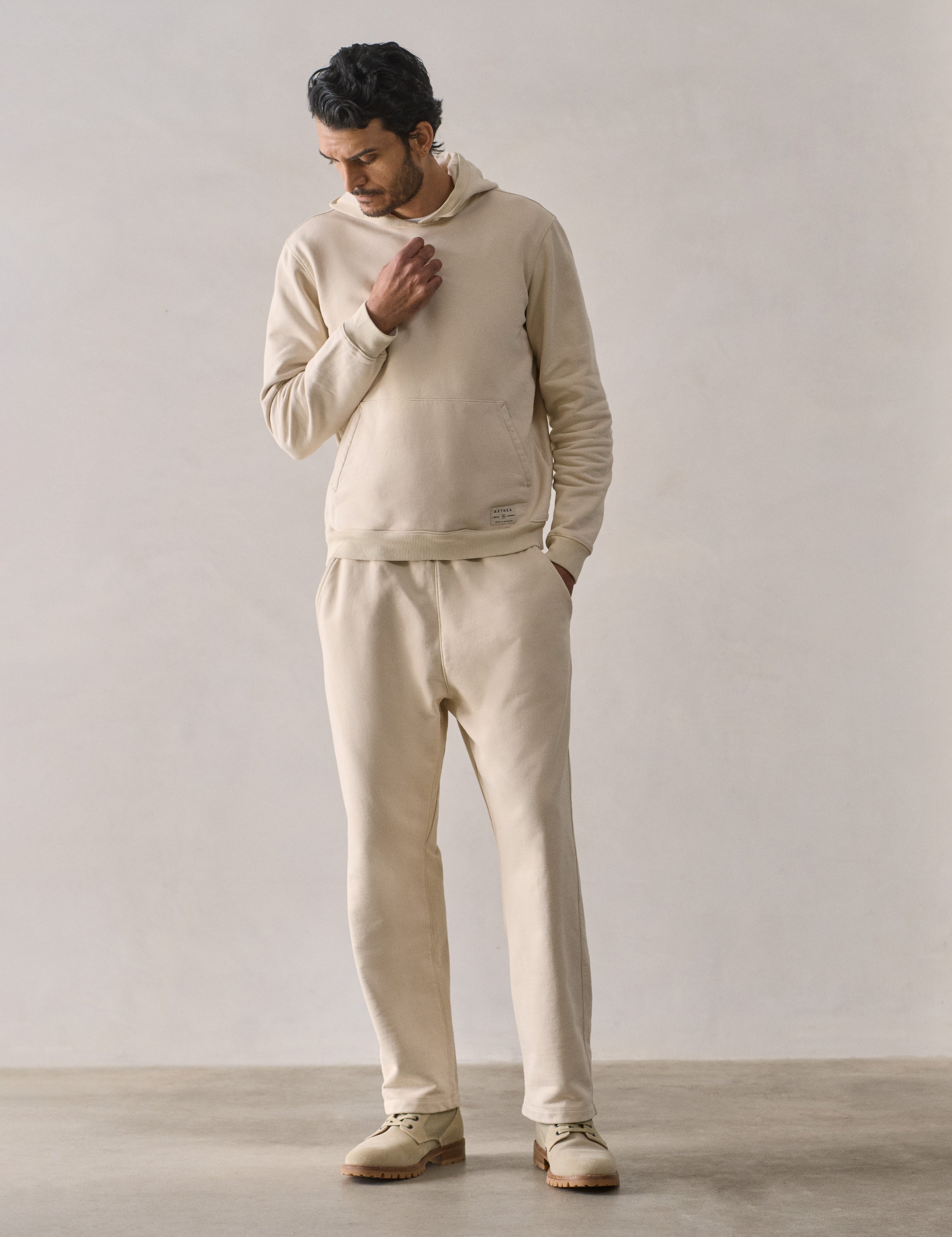 Front full-body view of man wearing Osa Pullover Hoodie in Bone white from AETHER Apparel.