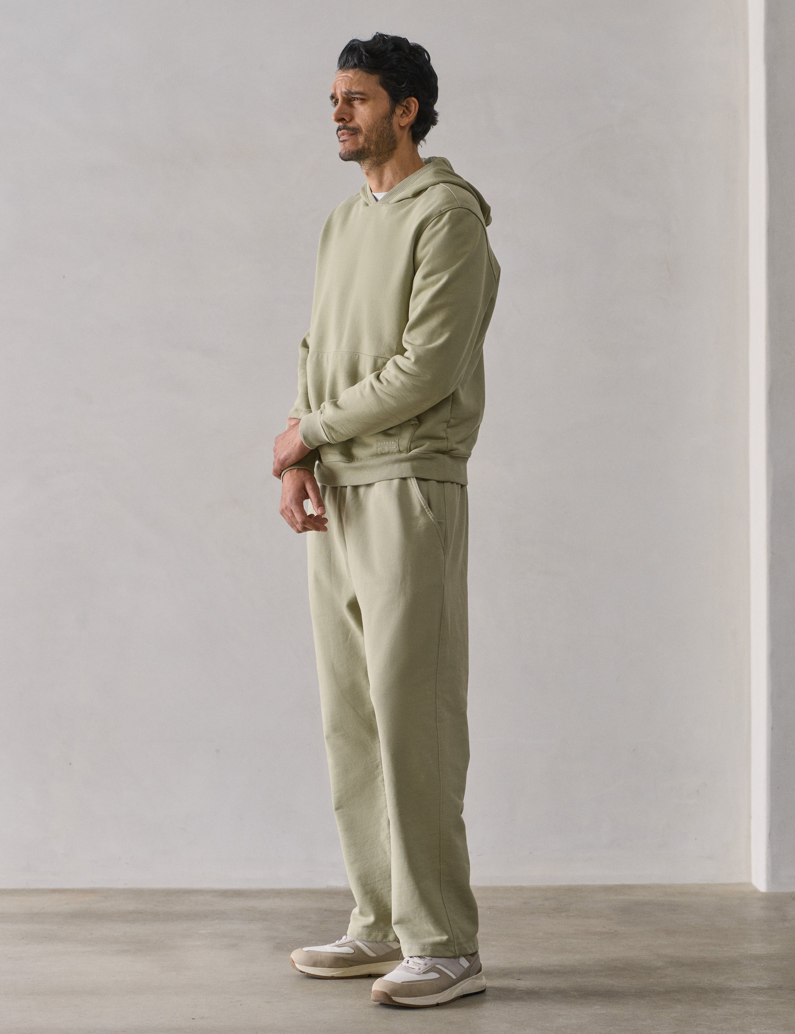 Front 3/4 full-body view of man wearing Osa Pullover Hoodie in Sage Green from AETHER Apparel.
