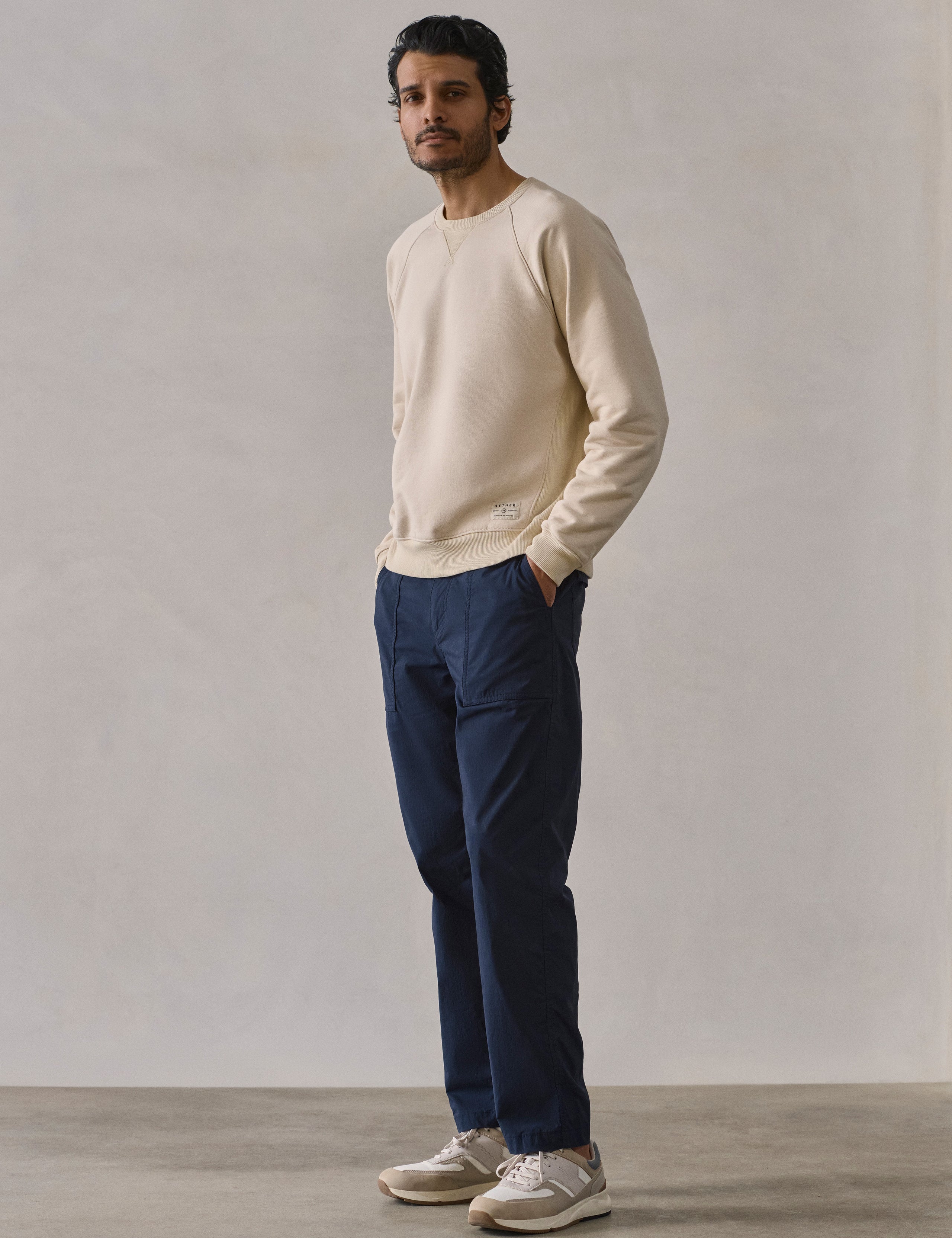 Front 3/4 full-body view of man wearing Osa Raglan Sweatshirt in Bone white from AETHER Apparel.