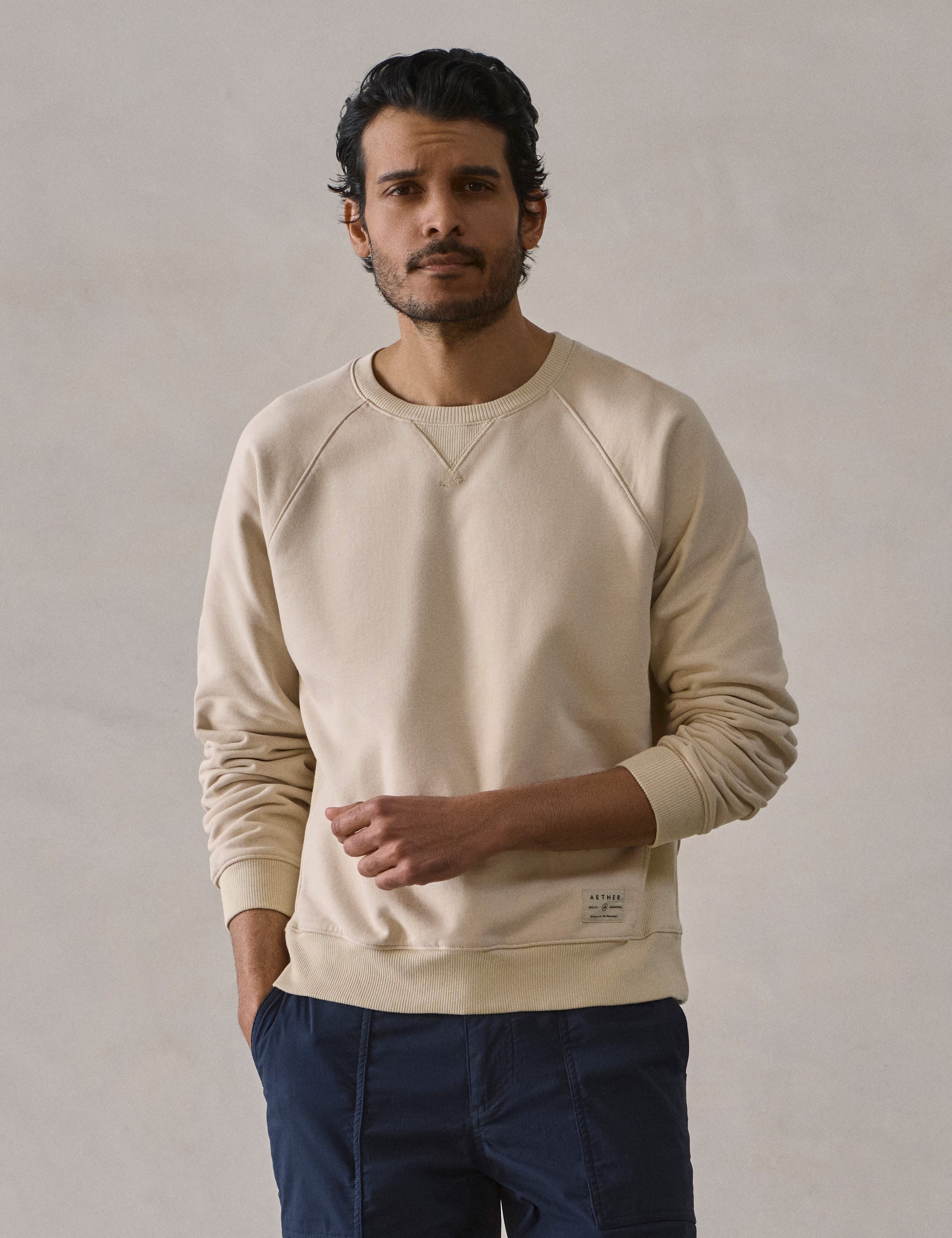 Front upper body view of man wearing Osa Raglan Sweatshirt in Bone white from AETHER Apparel.