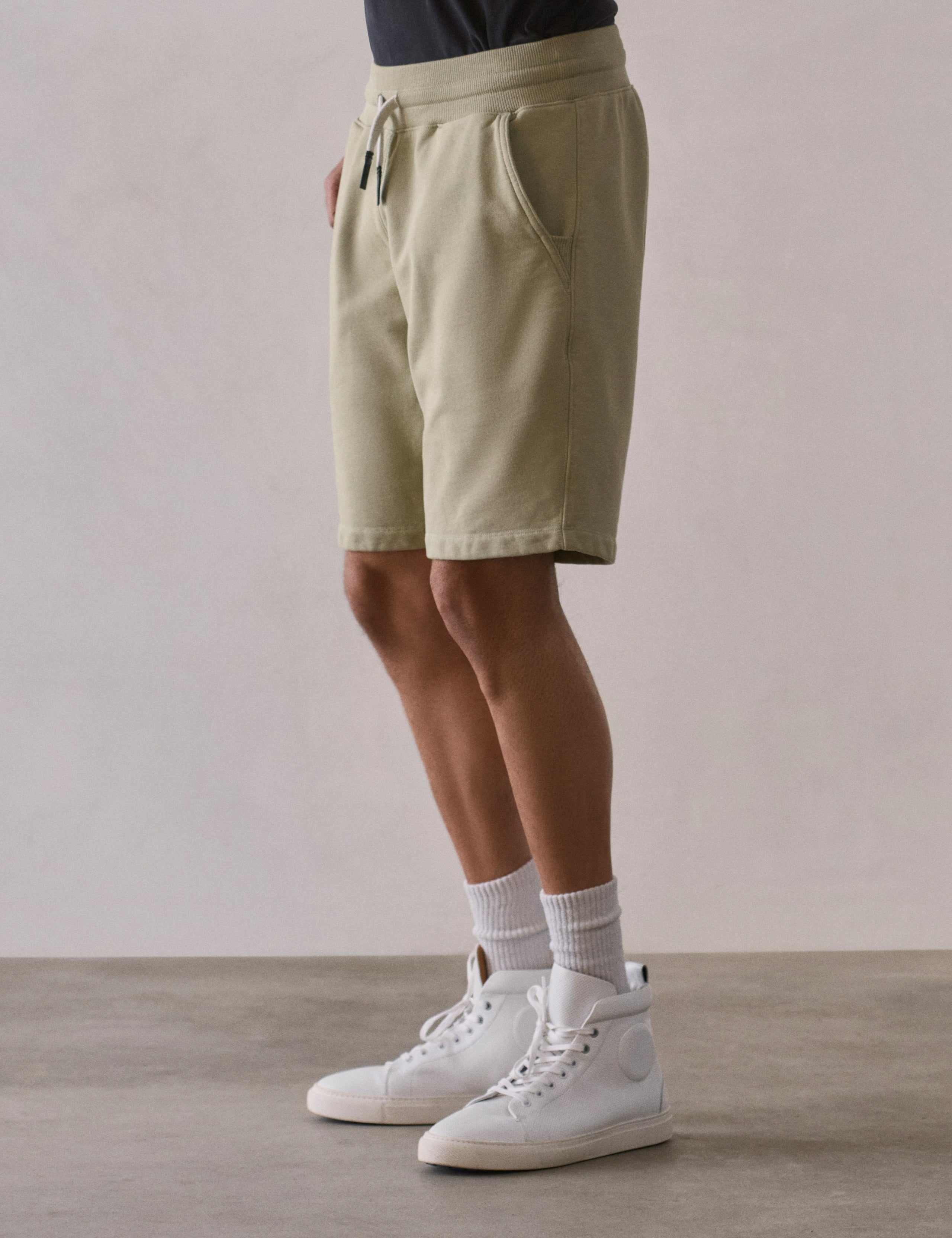 Front 3/4 lower body view of man wearing Osa Sweatshort in Sage Green from AETHER Apparel.
