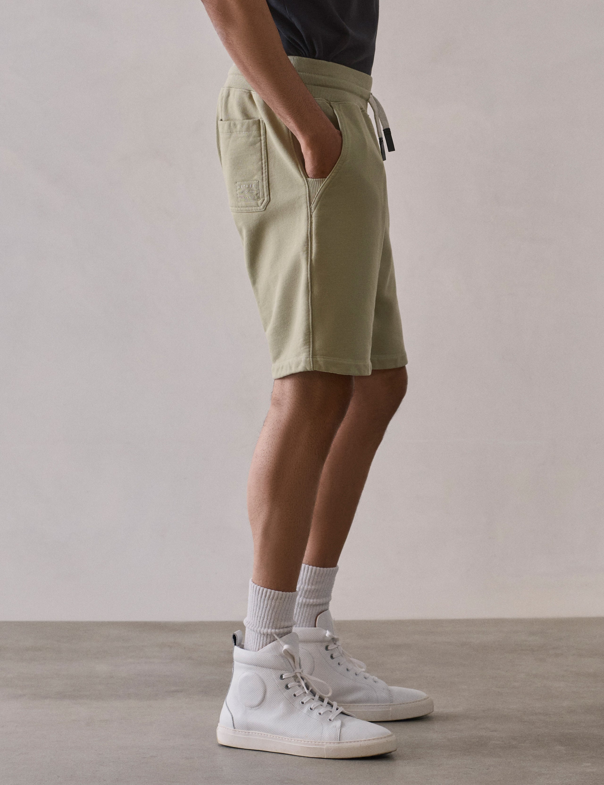 Right side lower body profile view of man wearing Osa Sweatshort in Sage Green from AETHER Apparel.
