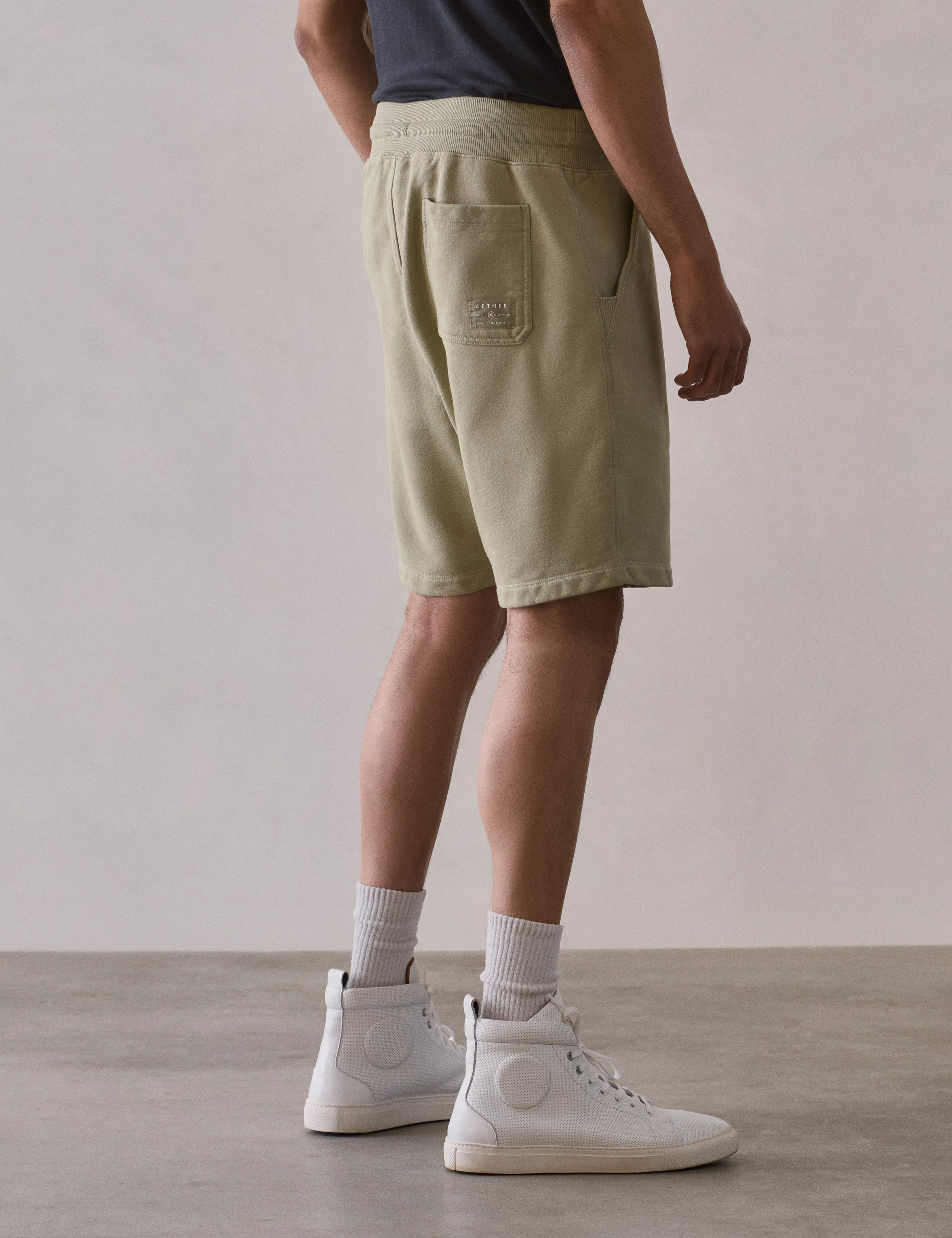 Rear 3/4 lower body view of man wearing Osa Sweatshort in Sage Green from AETHER Apparel.