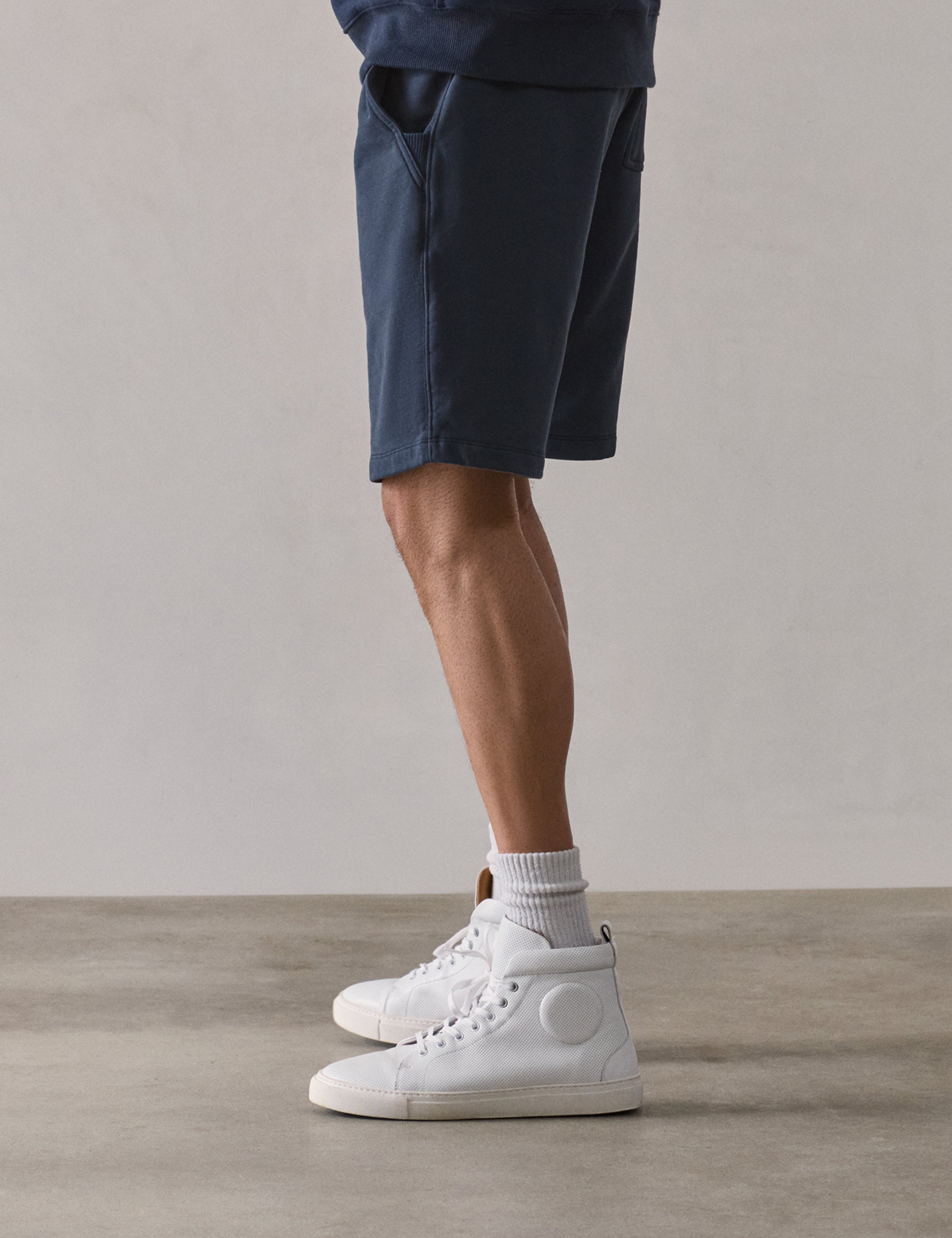 Left side profile lower-body view of man wearing Osa Sweatshort in Total Eclipse dark blue from AETHER Apparel.