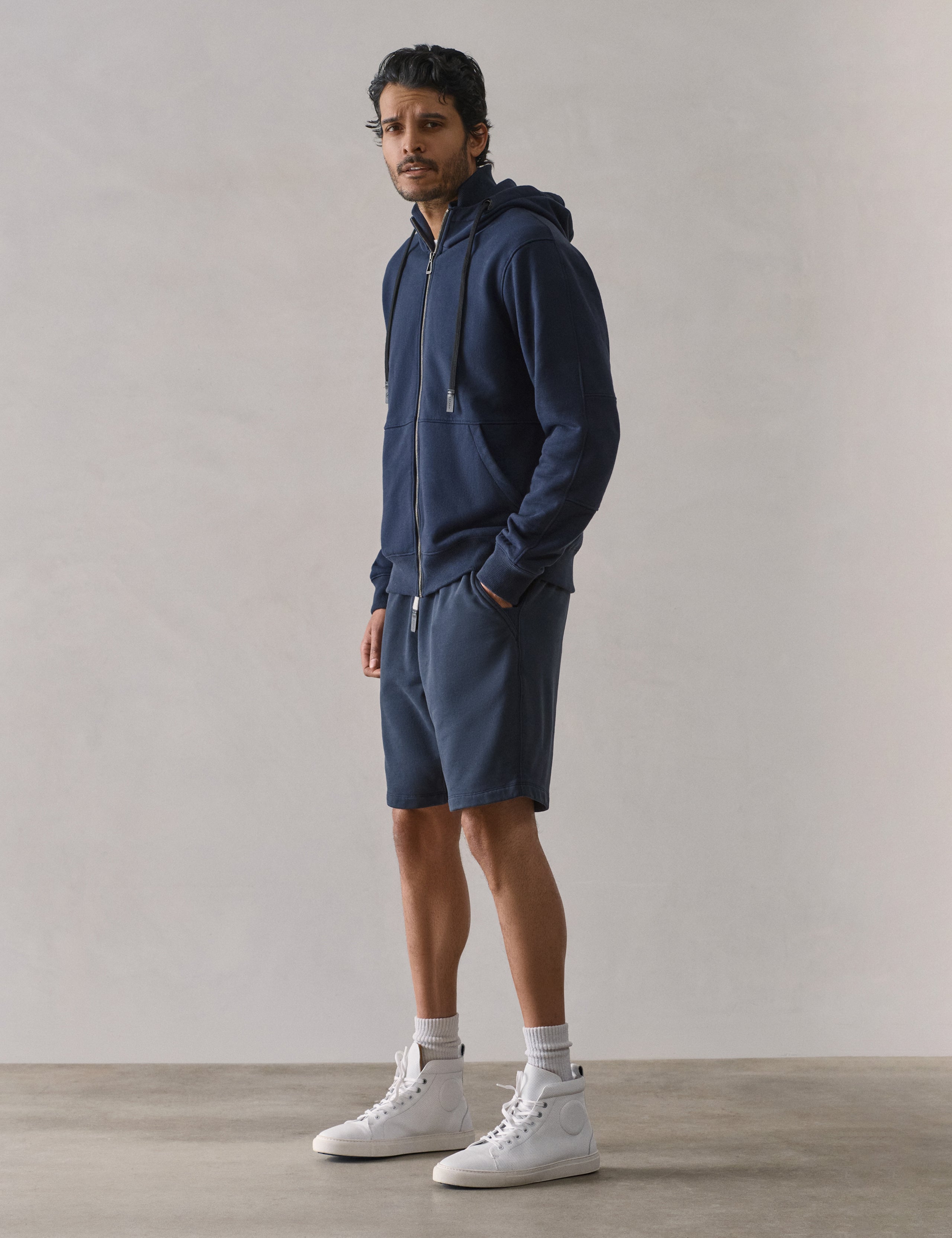 Front 3/4 full-body view of man wearing Osa Sweatshort in Total Eclipse dark blue from AETHER Apparel.