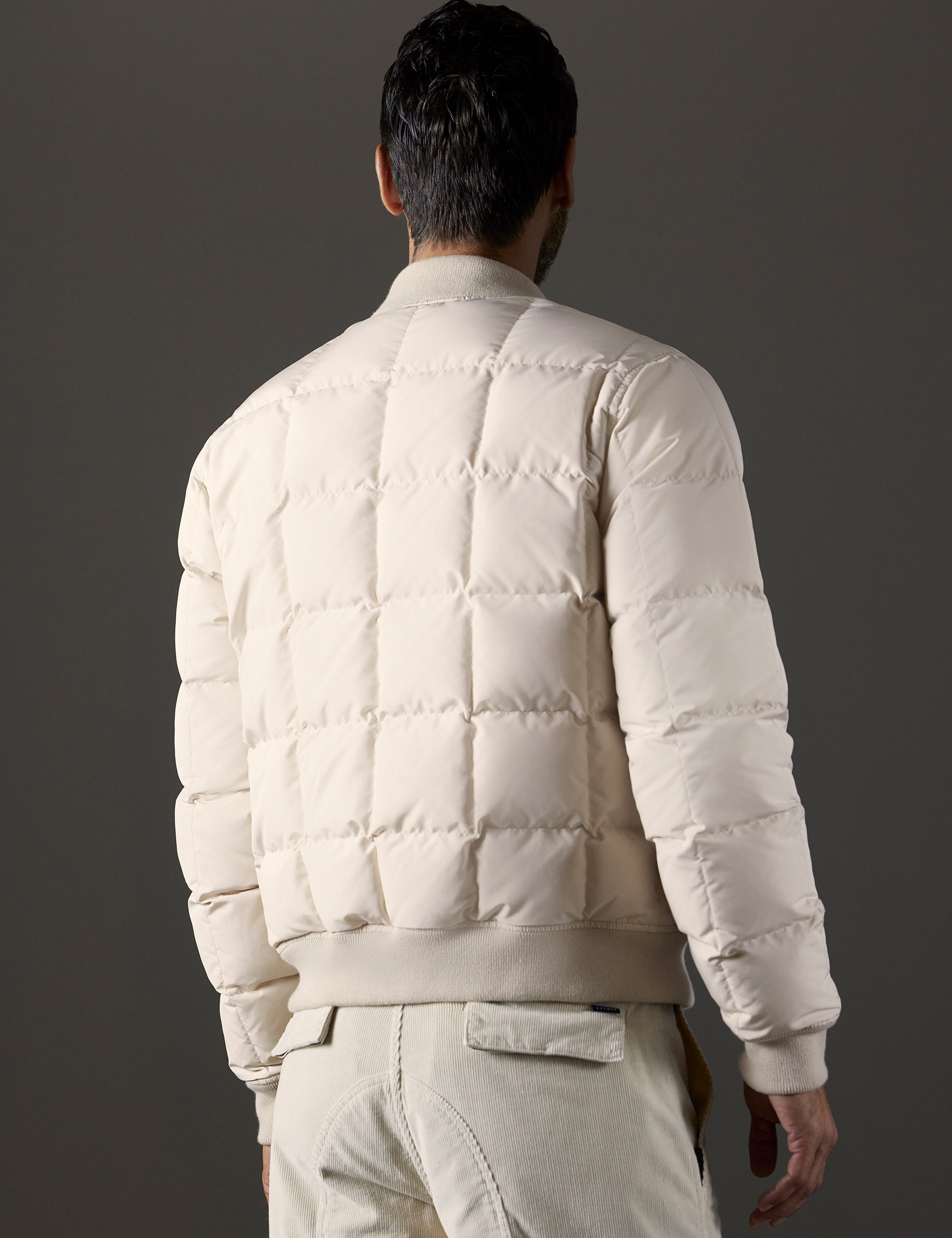 Rear 3/4 body view of man wearing Pacer Jacket in Bone white from AETHER Apparel.