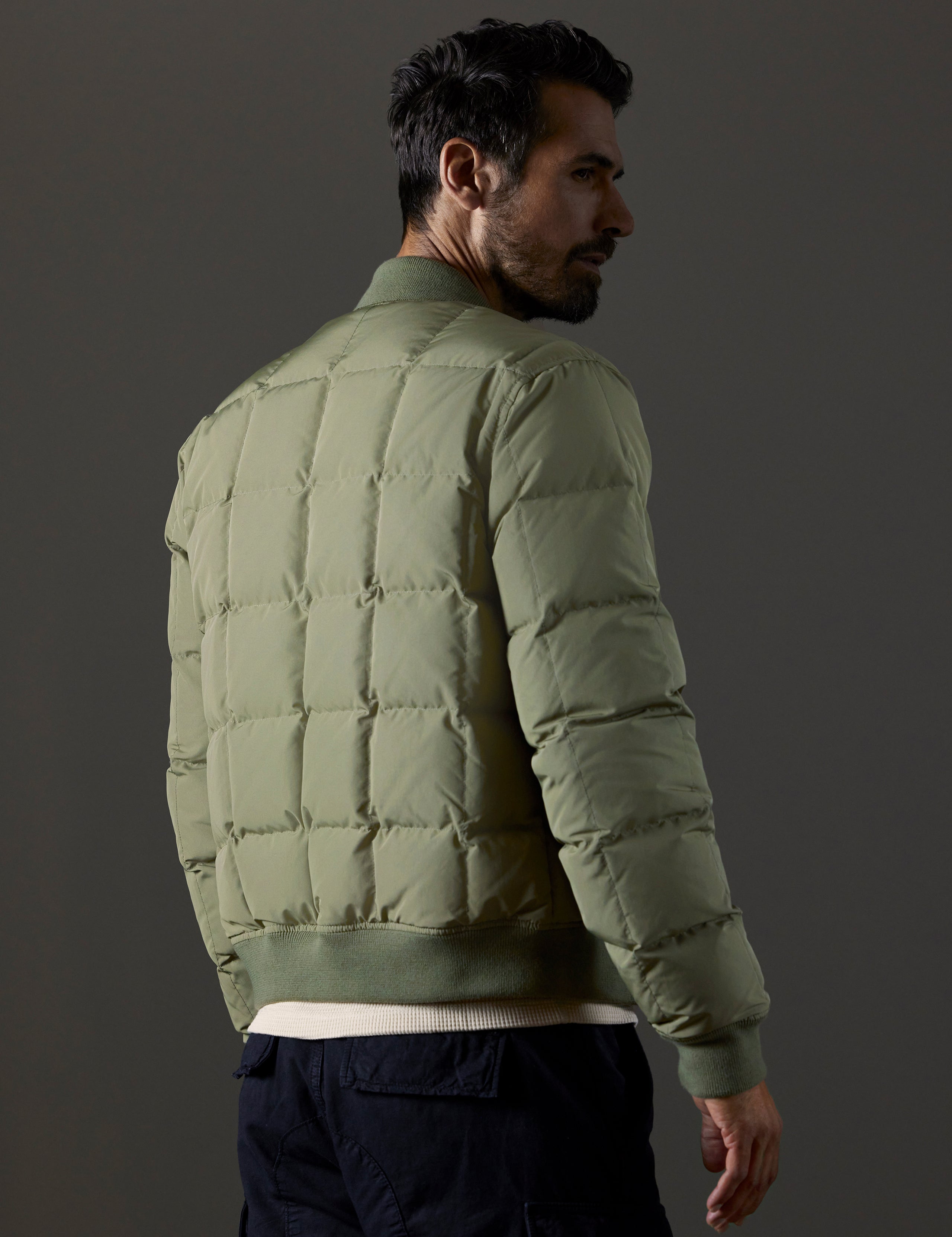 Rear 3/4 body view of man wearing Pacer Jacket in Fern Green from AETHER Apparel.
