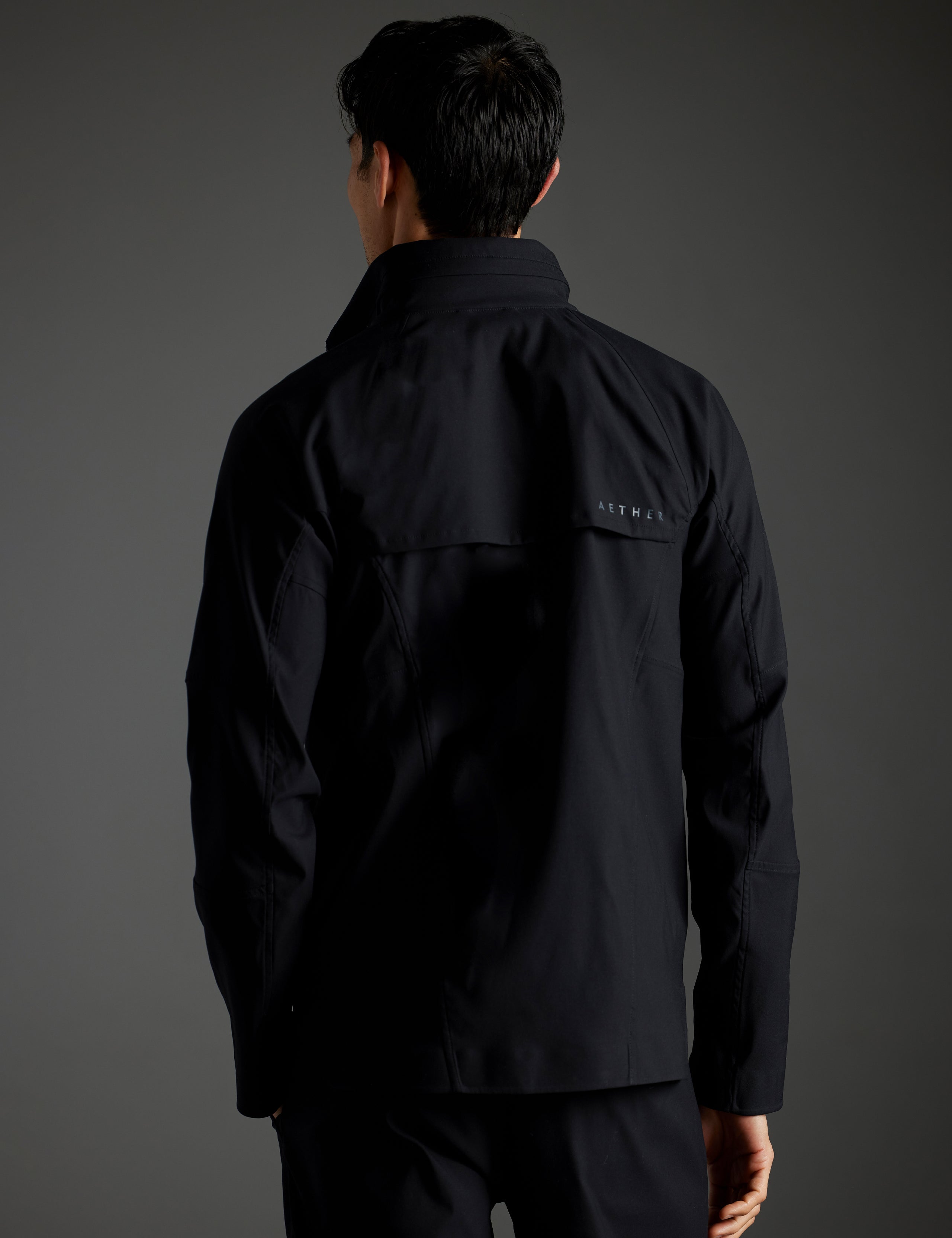 Rear body view of man wearing Perth Vented Jacket in Onyx Black from AETHER Apparel.