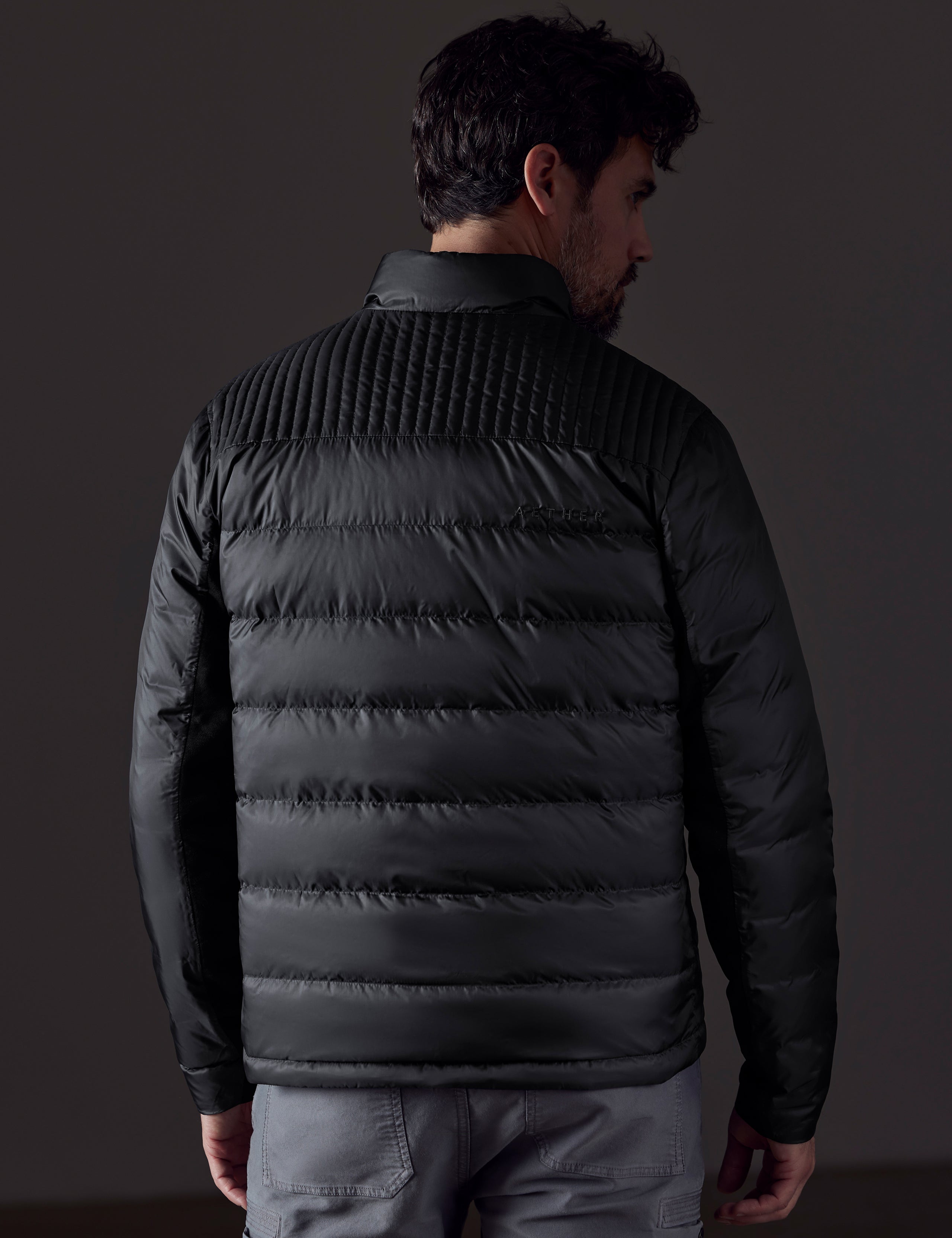 Rear body view of man wearing Phantom Jacket in Onyx Black from AETHER Apparel.