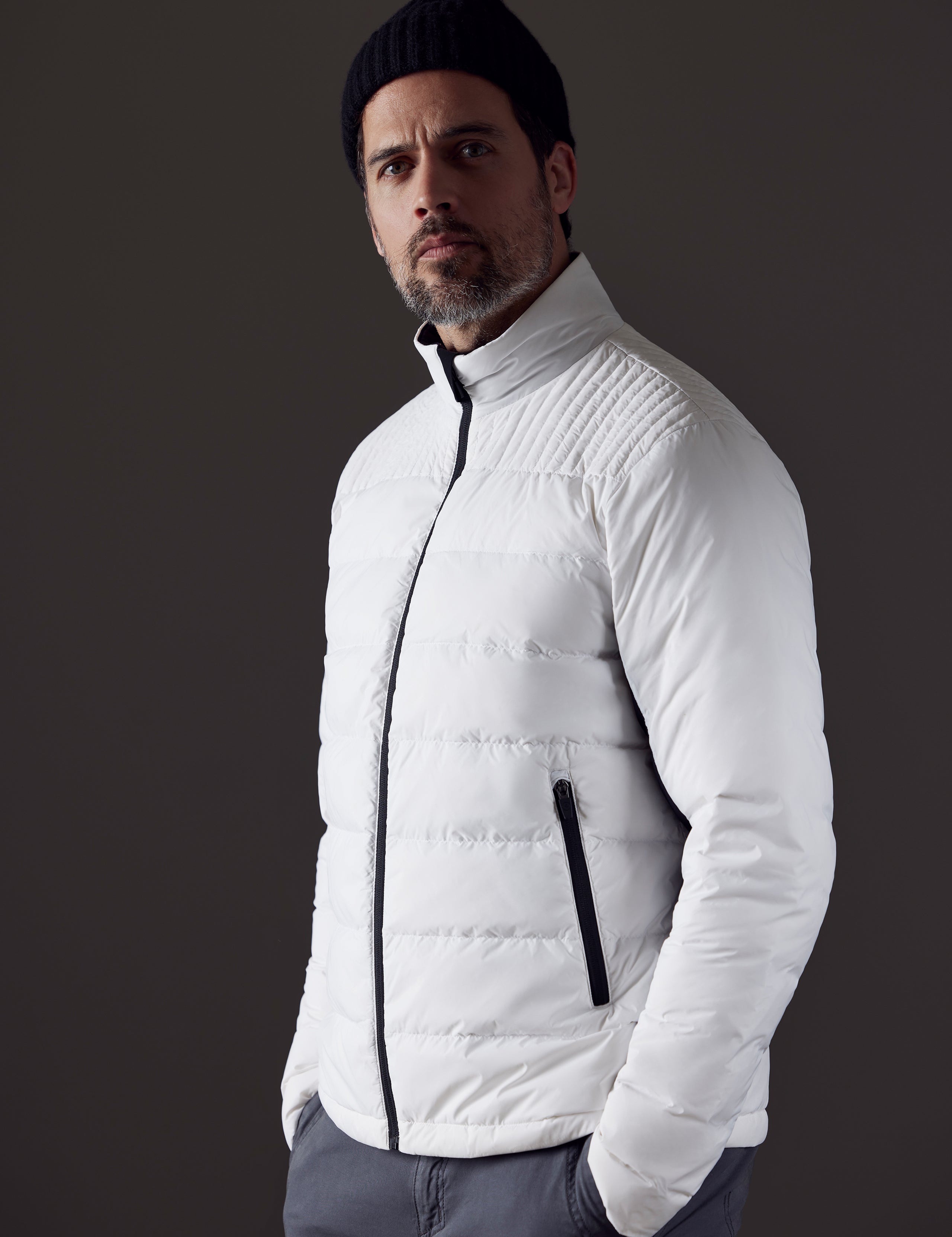 Front 3/4 body view of man with hands in pant pockets wearing Phantom Jacket in White from AETHER Apparel.
