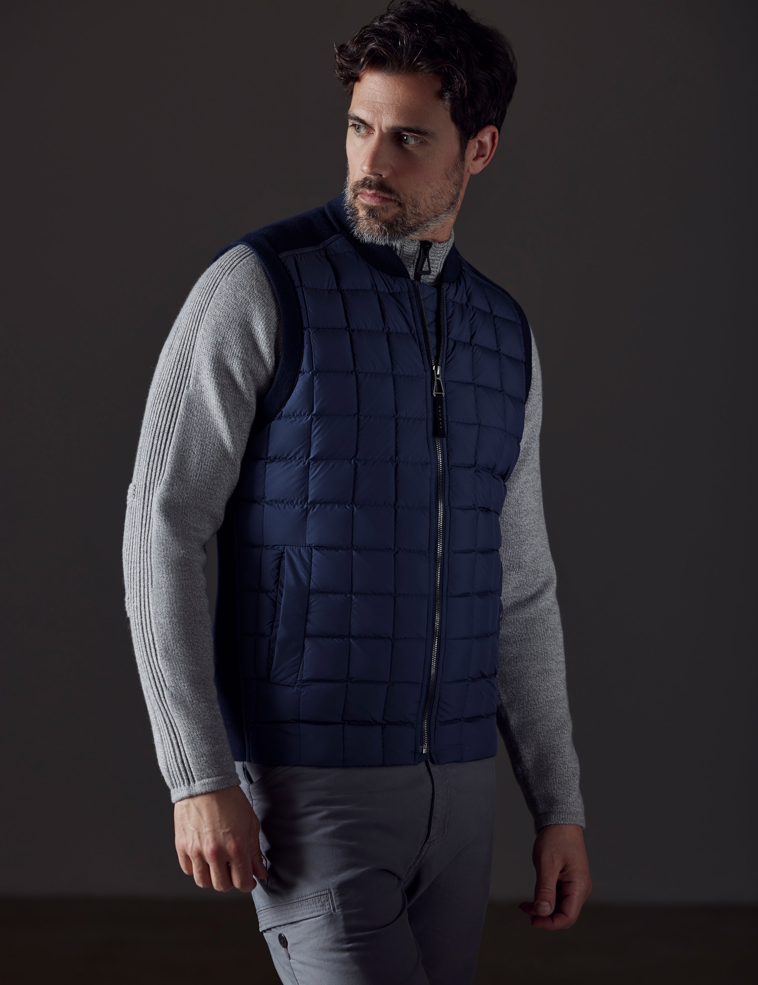 Front 3/4 body view of man looking over shoulder wearing Phase Vest in Total Eclipse dark blue from AETHER Apparel.