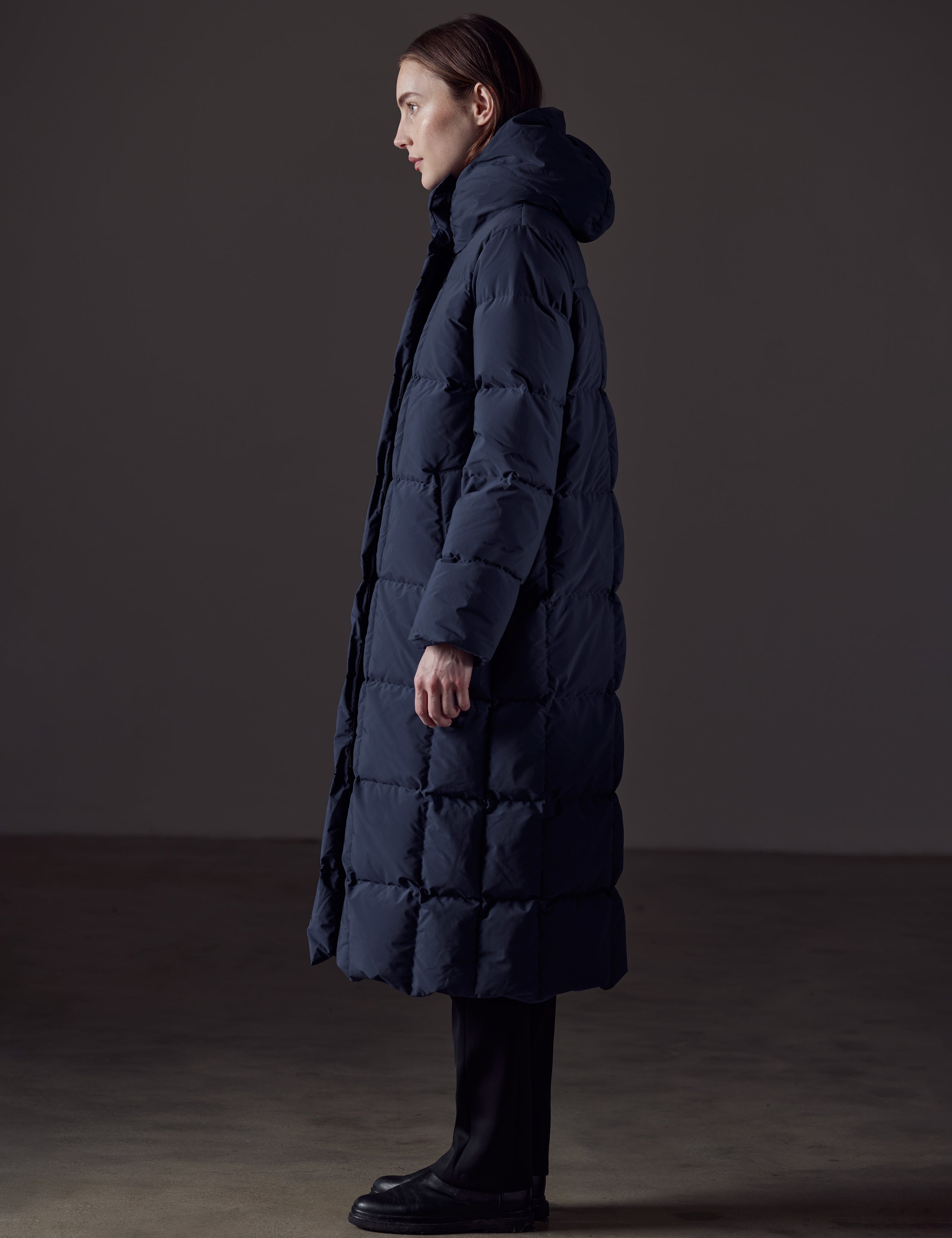 Side profile full-body view of woman wearing Shaw Jacket in Nordic Navy Blue from AETHER Apparel.