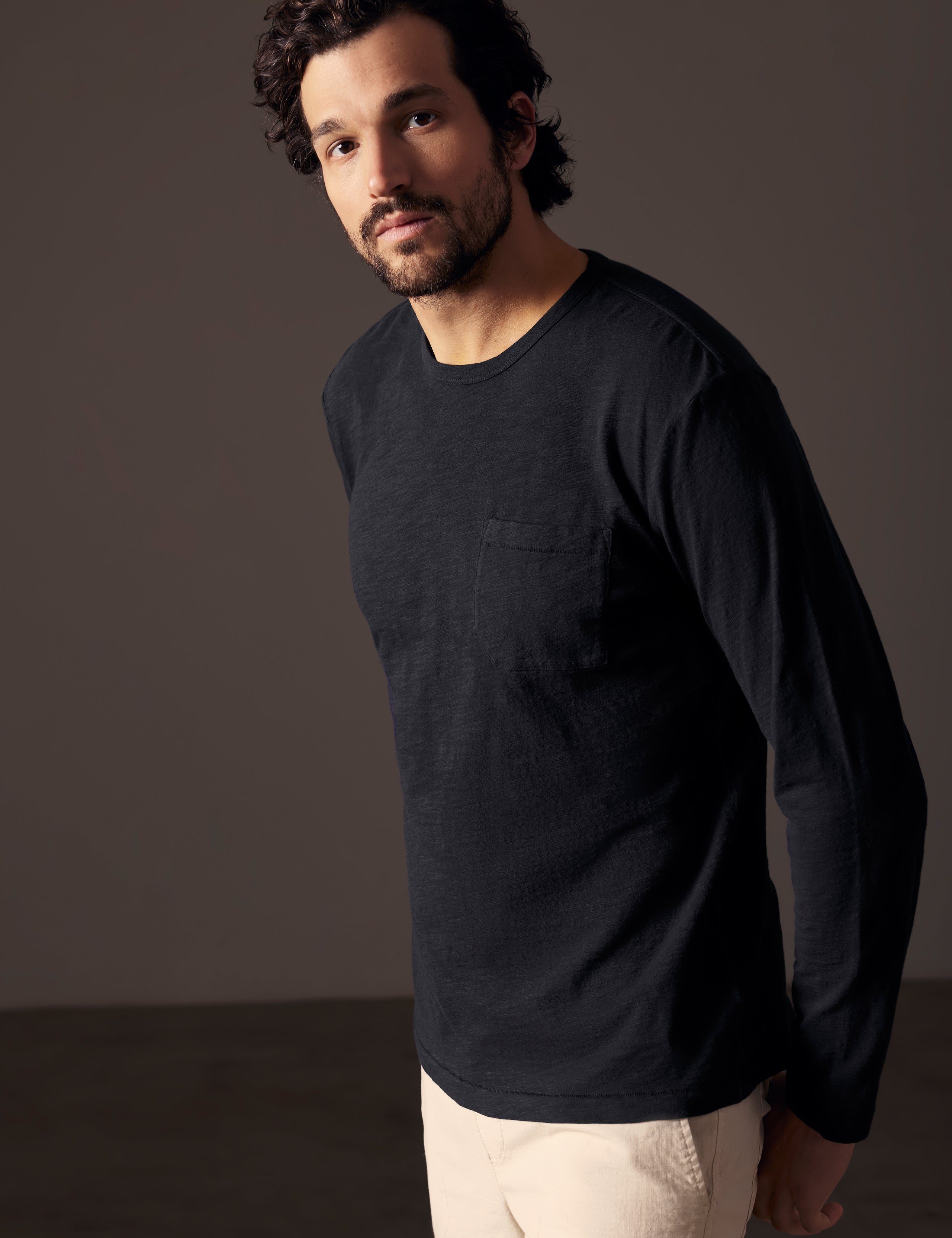 Front angled body view of man wearing Slub Long-Sleeve Tee in Onyx Black from AETHER Apparel.