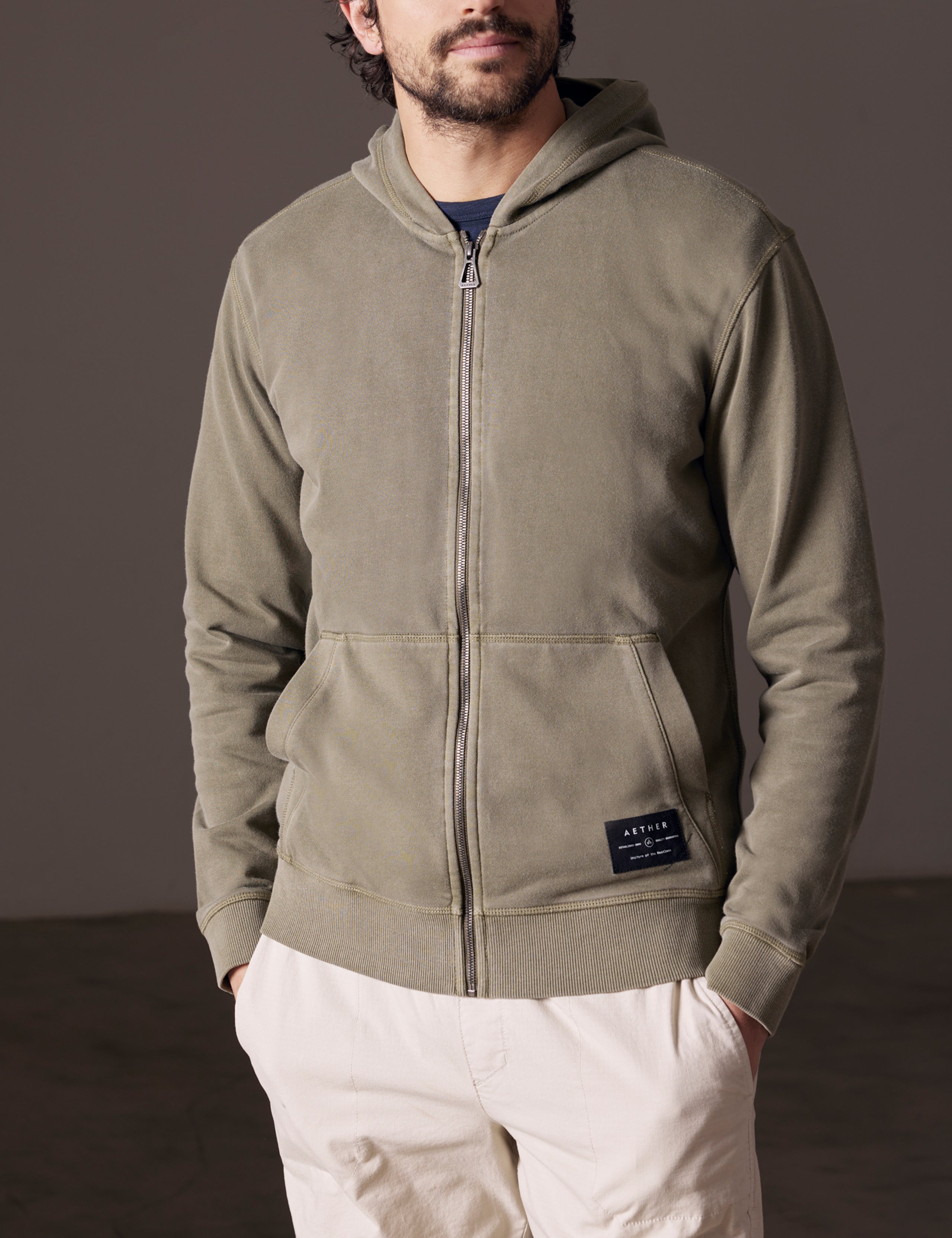 Front body view of man wearing Solstice Lightweight Full-Zip Hoodie in Command Green from AETHER Apparel.