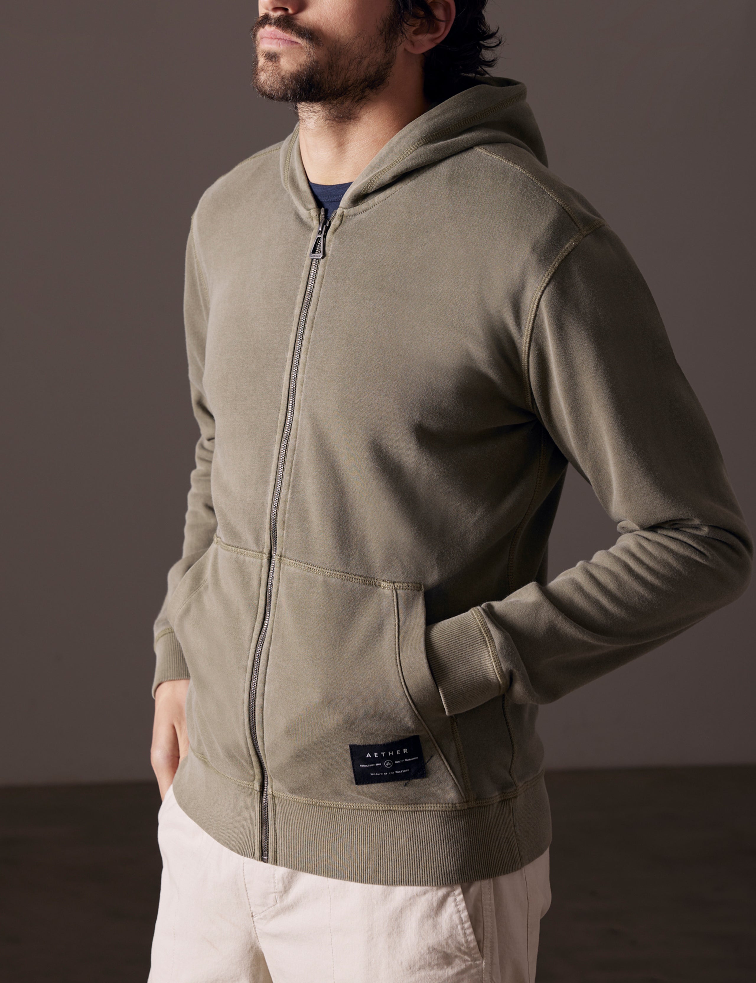 Front 3/4 body view of man wearing Solstice Lightweight Full-Zip Hoodie in Command Green from AETHER Apparel.