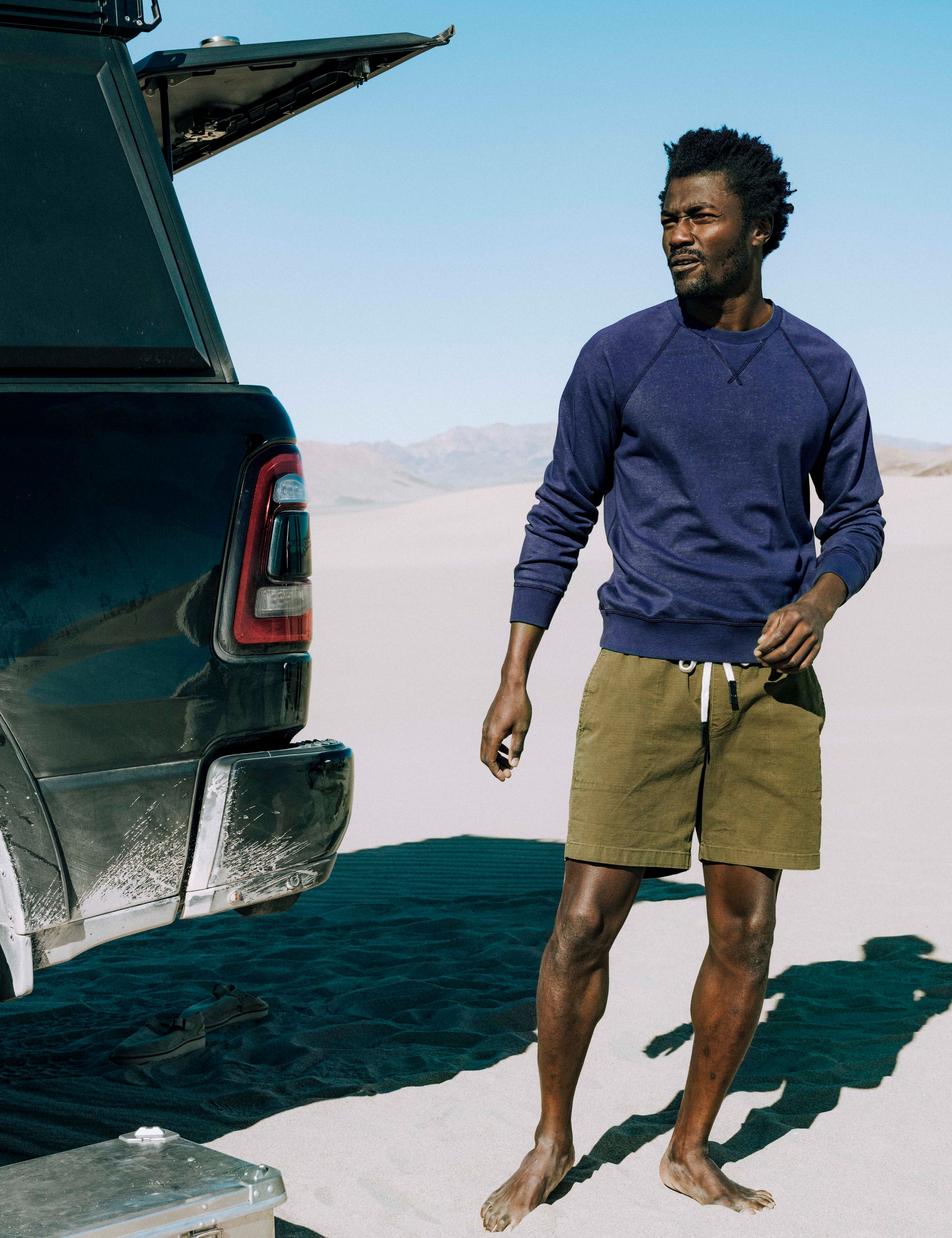 Outdoor lifestyle view of man standing next to pickup truck wearing Solstice Lightweight Crew in Total Eclipse dark blue from AETHER Apparel.