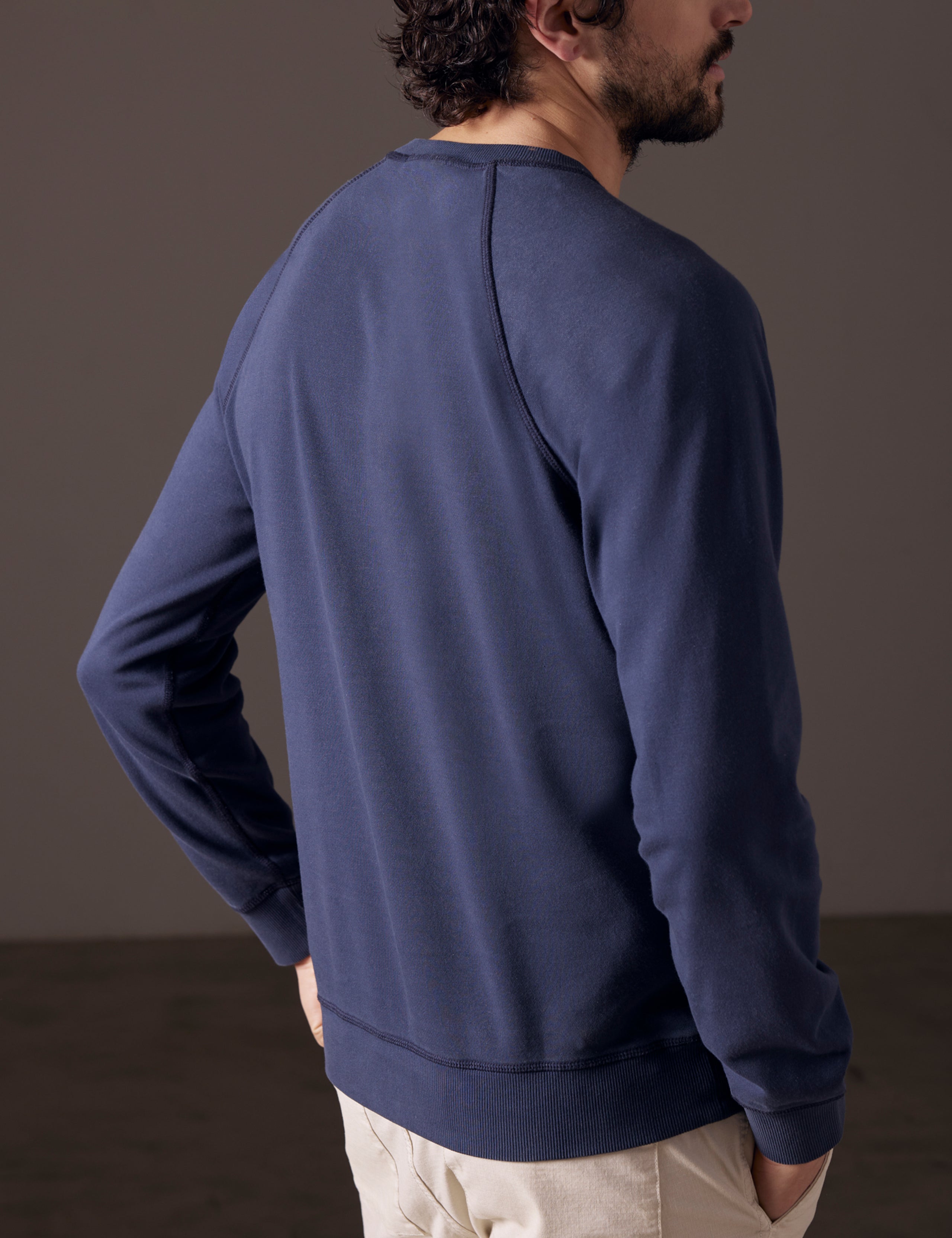Rear 3/4 body view of man wearing Solstice Lightweight Crew in Total Eclipse dark blue from AETHER Apparel.