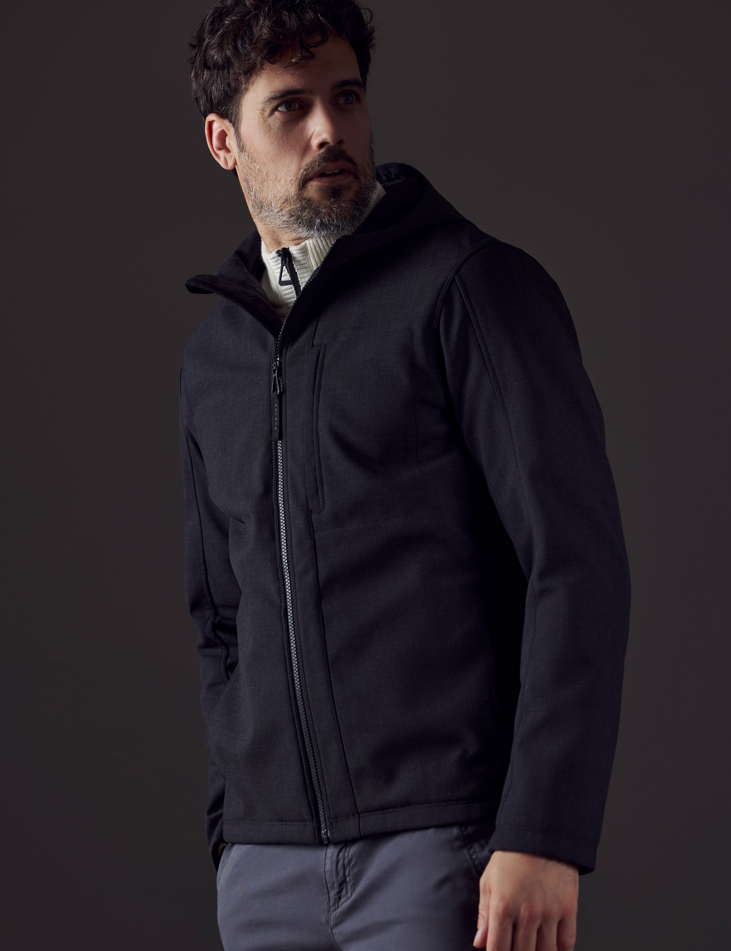 Front 3/4 body view of man looking over shoulder wearing Stanton Technical Jacket in Charcoal Heather from AETHER Apparel.