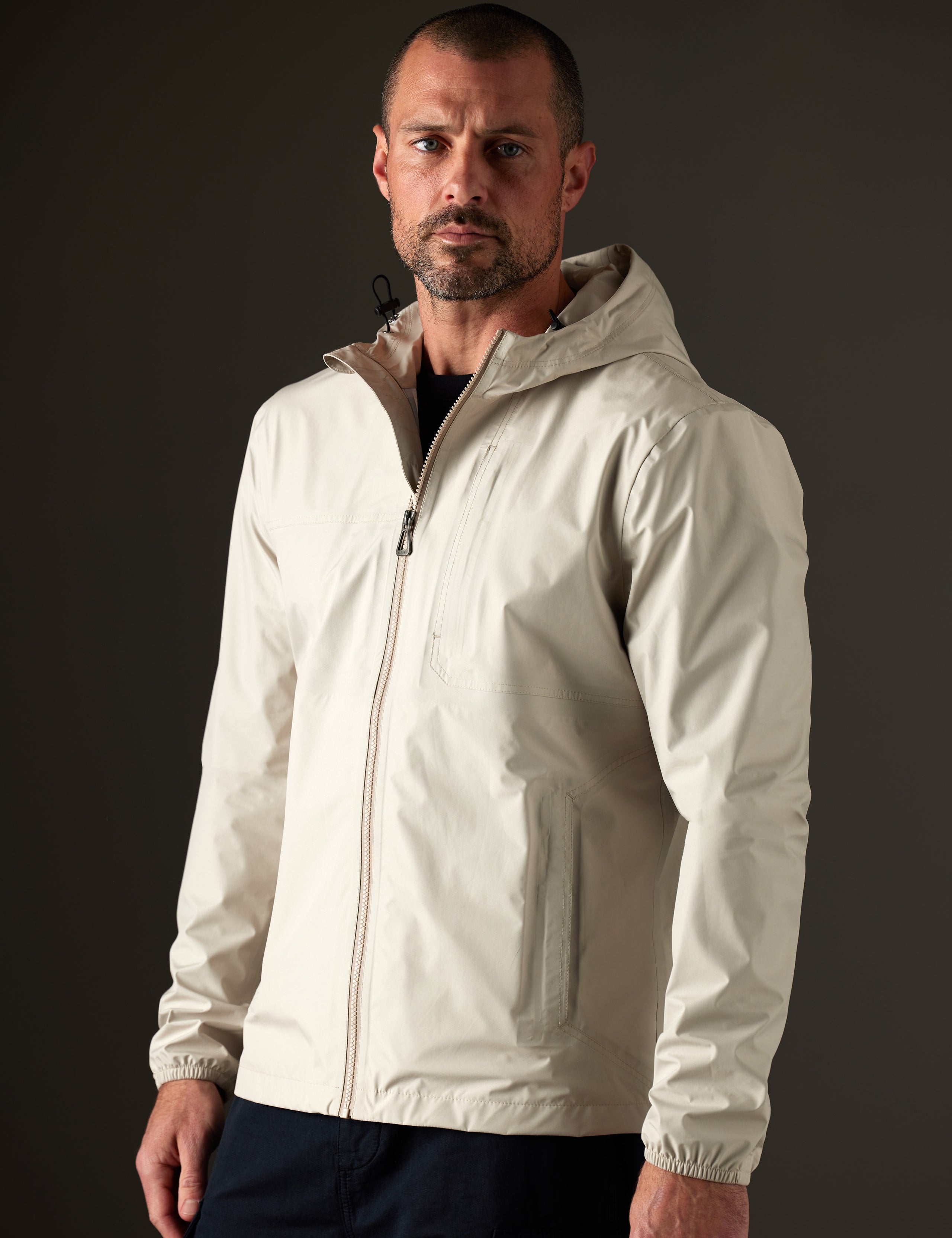Front 3/4 body view of man wearing Storm All-Weather Jacket in Bone white from AETHER Apparel.
