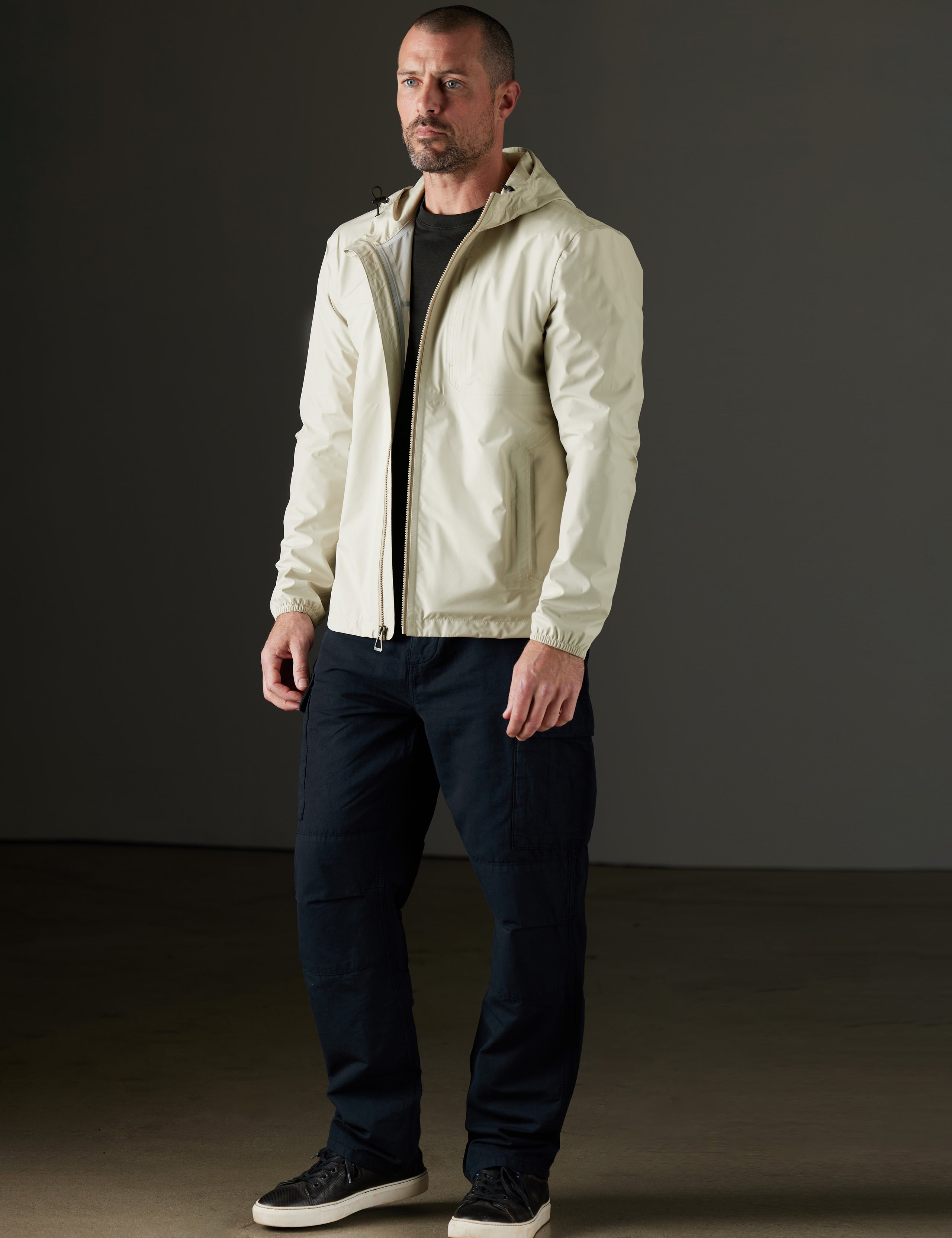 Front 3/4 full-body view of man wearing Storm All-Weather Jacket in Bone white from AETHER Apparel.