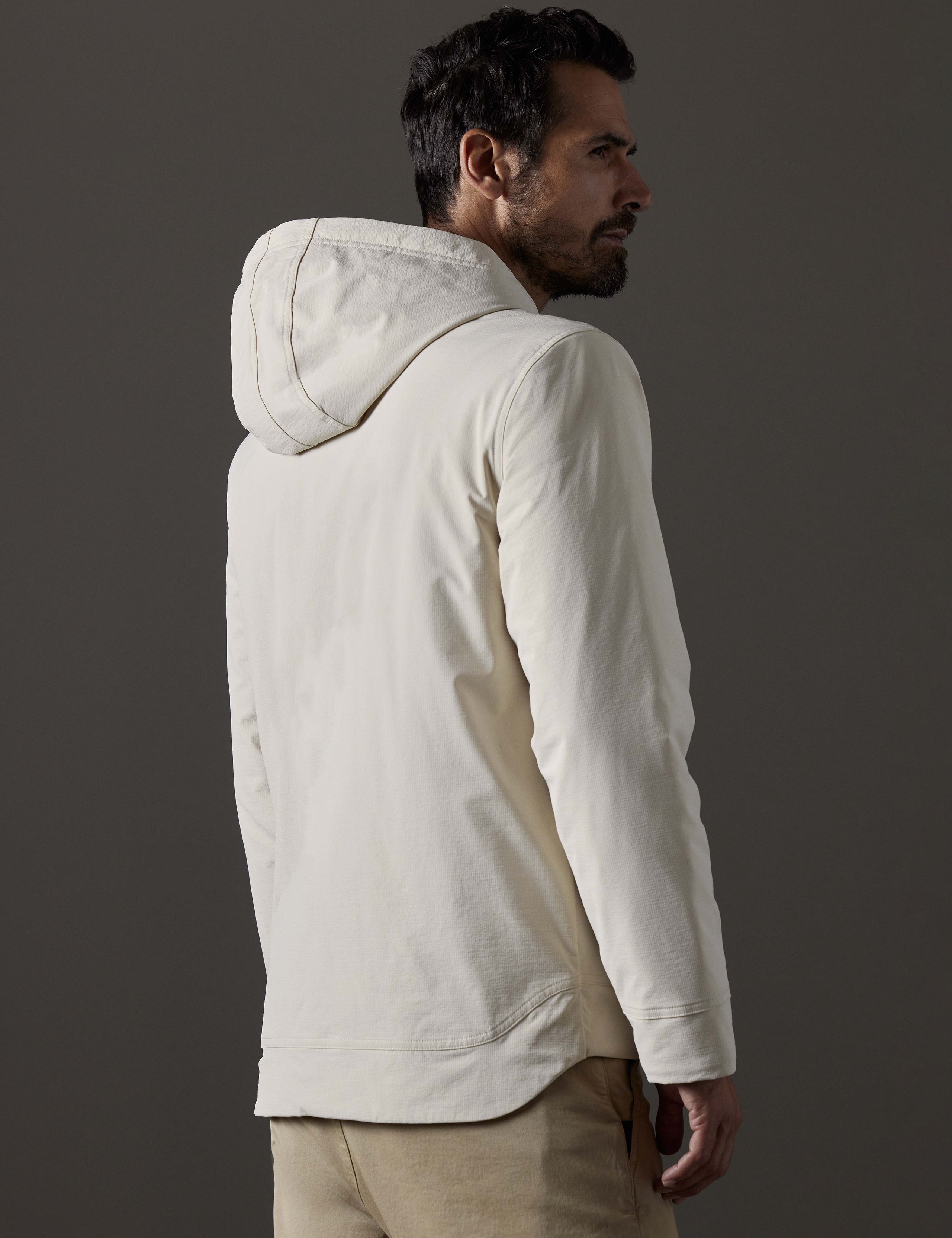 Rear 3/4 body view of man wearing Stornaway Insulated Hoodie in Bone white from AETHER Apparel.
