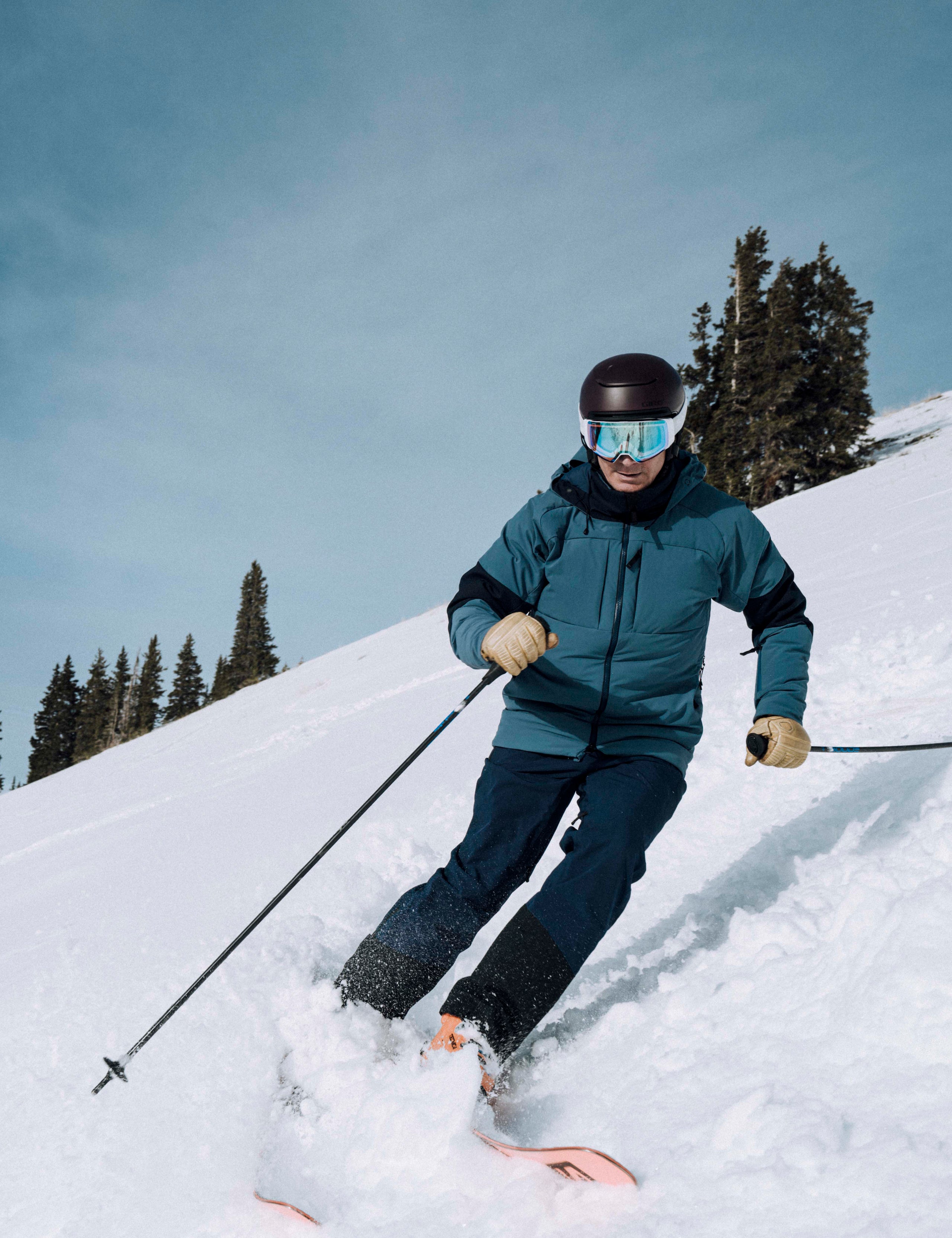 Outdoor lifestyle image of man skiing down hill wearing Torino Jacket in Baltic Blue from AETHER Apparel.
