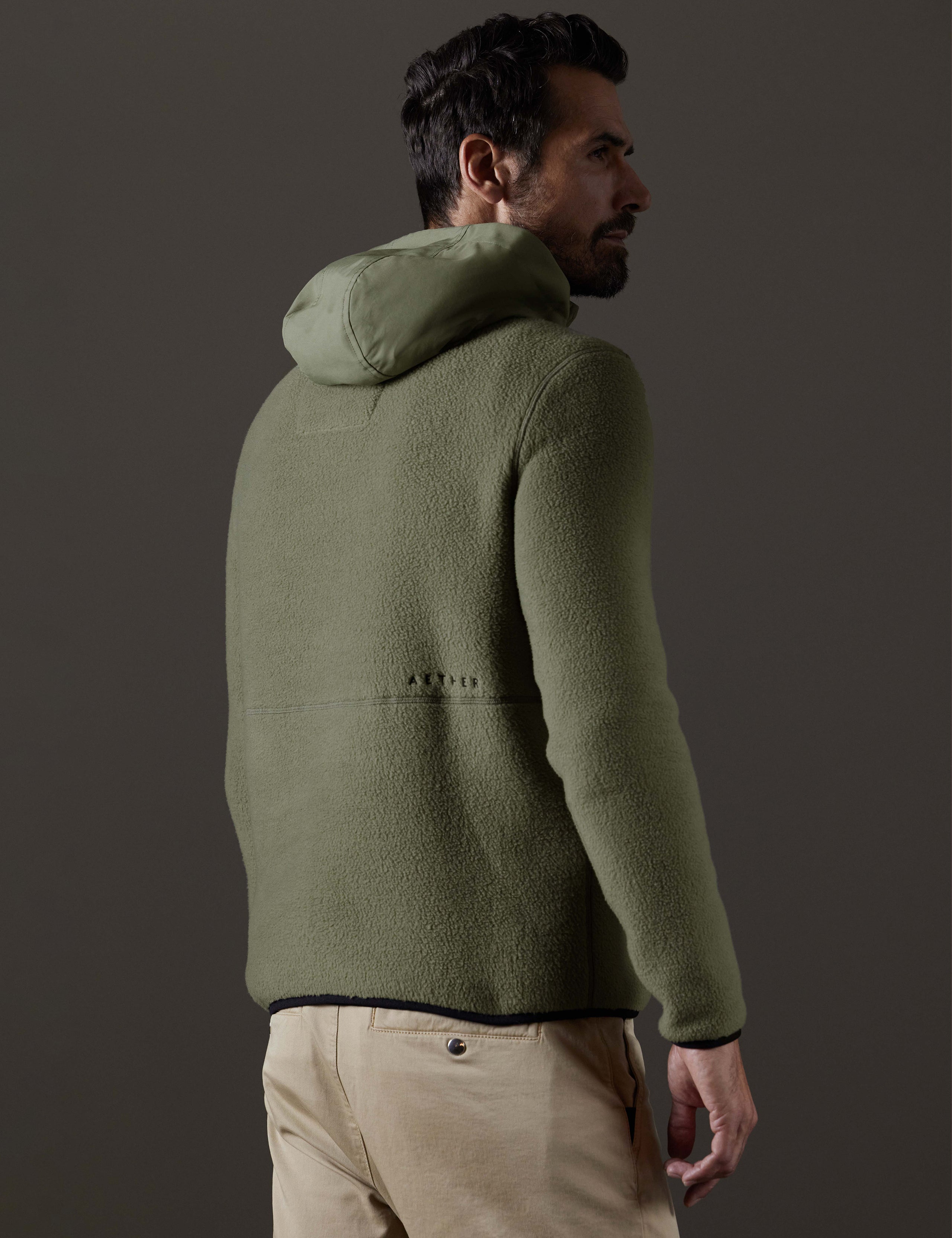 Rear 3/4 body view of man wearing Walsh Hooded Anorak in Fern Green from AETHER Apparel.