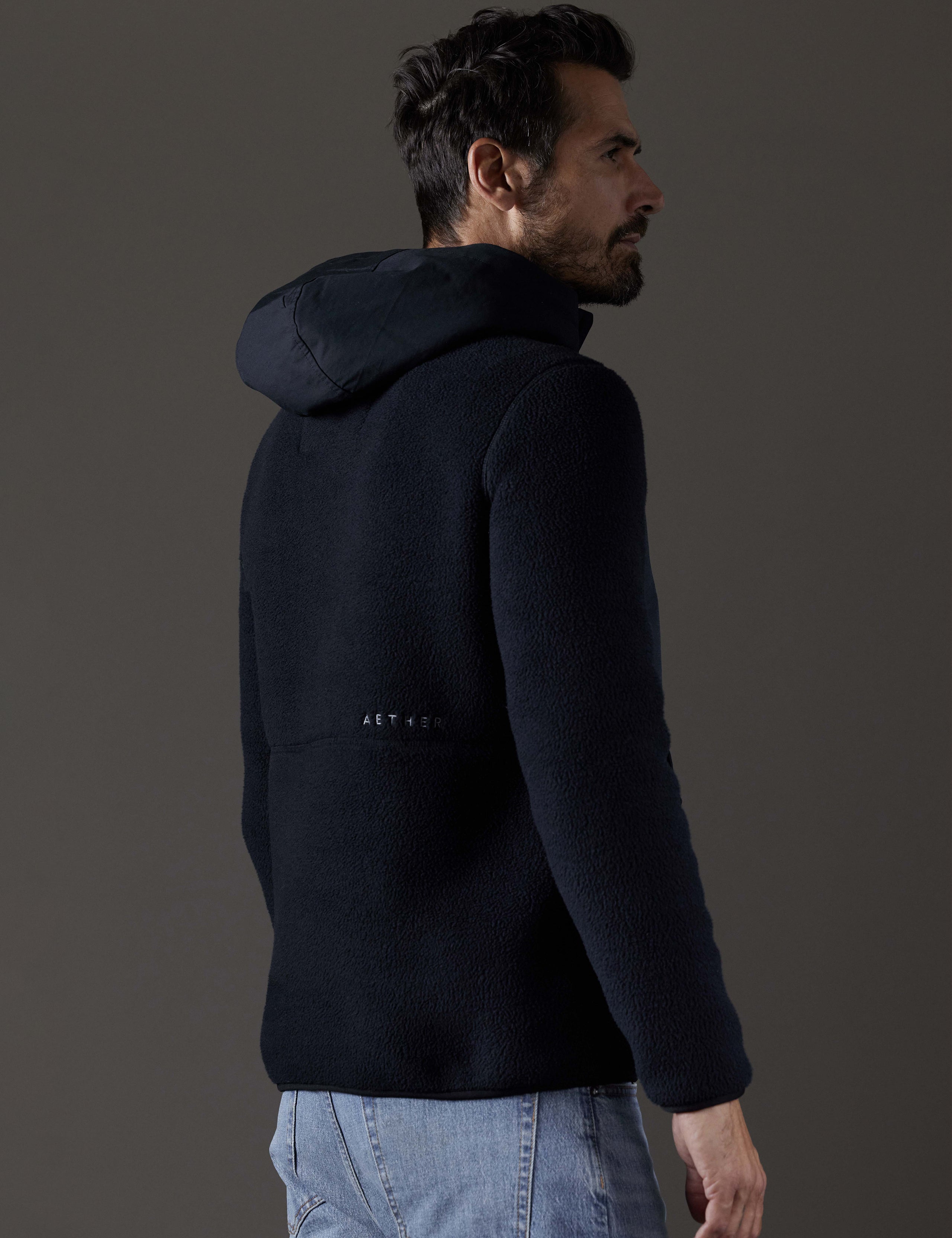 Rear 3/4 body view of man wearing Walsh Hooded Anorak in Onyx Black from AETHER Apparel.