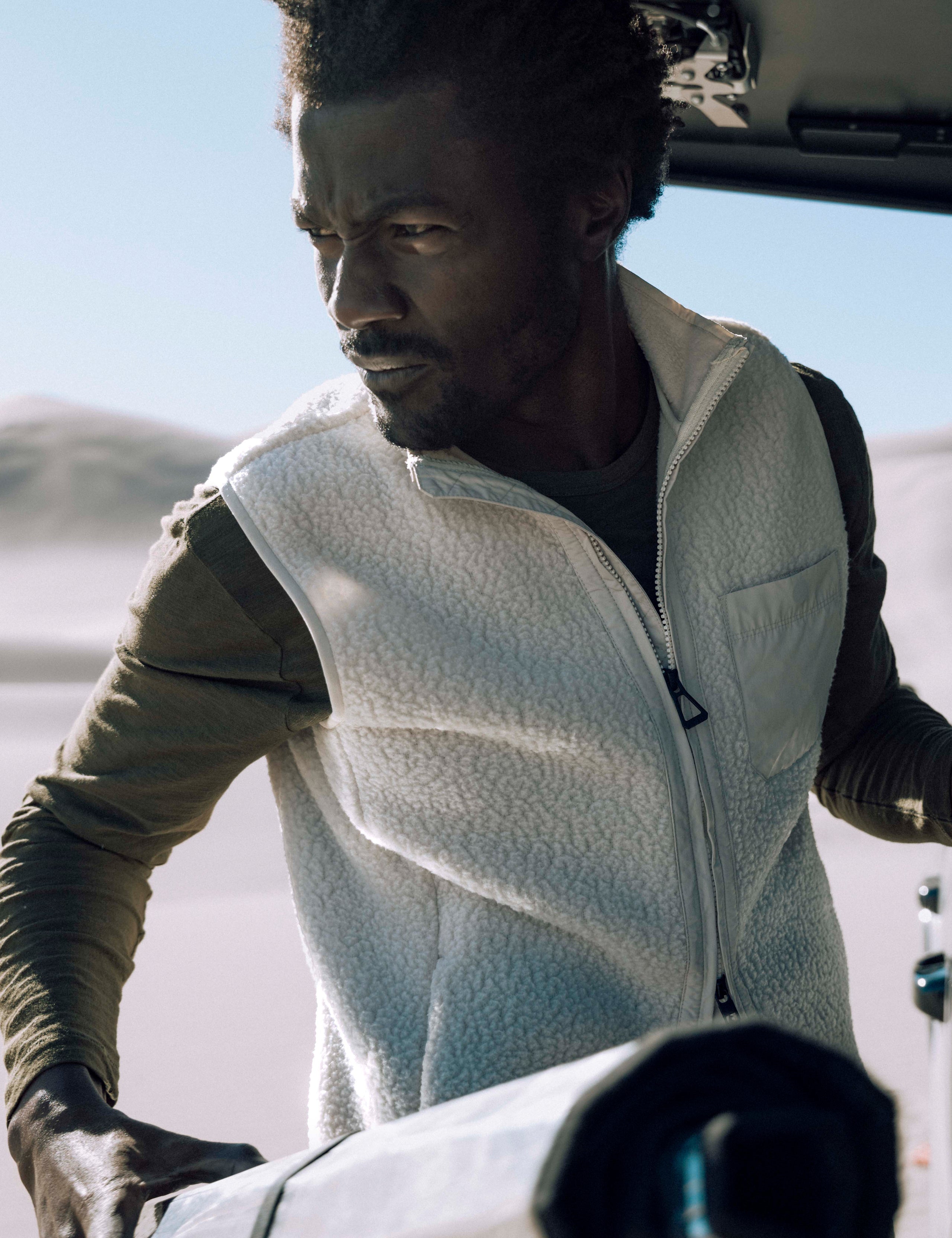 Outdoor lifestyle image of man wearing Walsh Vest in Bone white from AETHER Apparel.