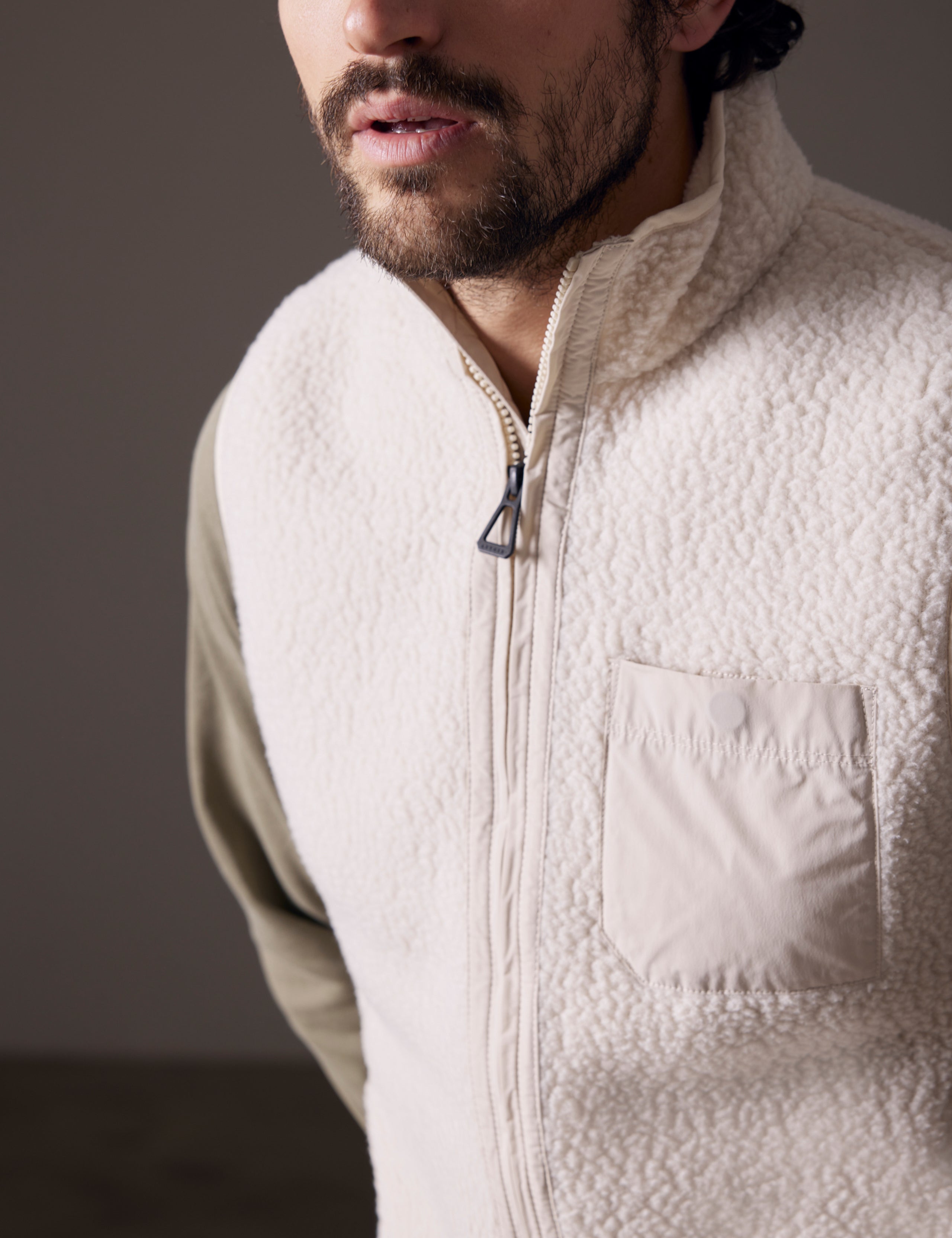Closeup detailed view of main zipper, chest pocket, and fabric of Walsh Vest in Bone white from AETHER Apparel.
